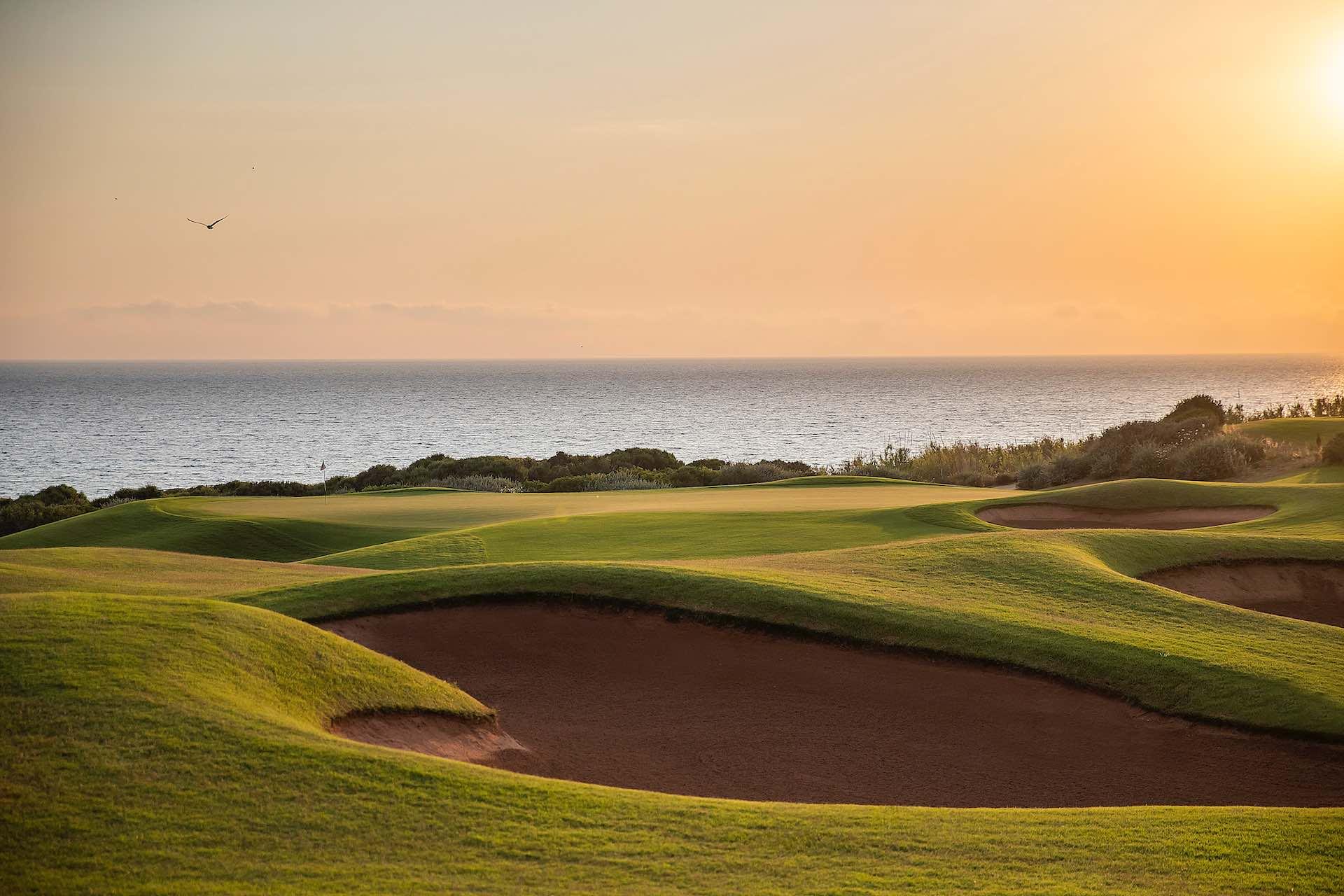 A deep sand bunker nestled next to a smooth green under the sun