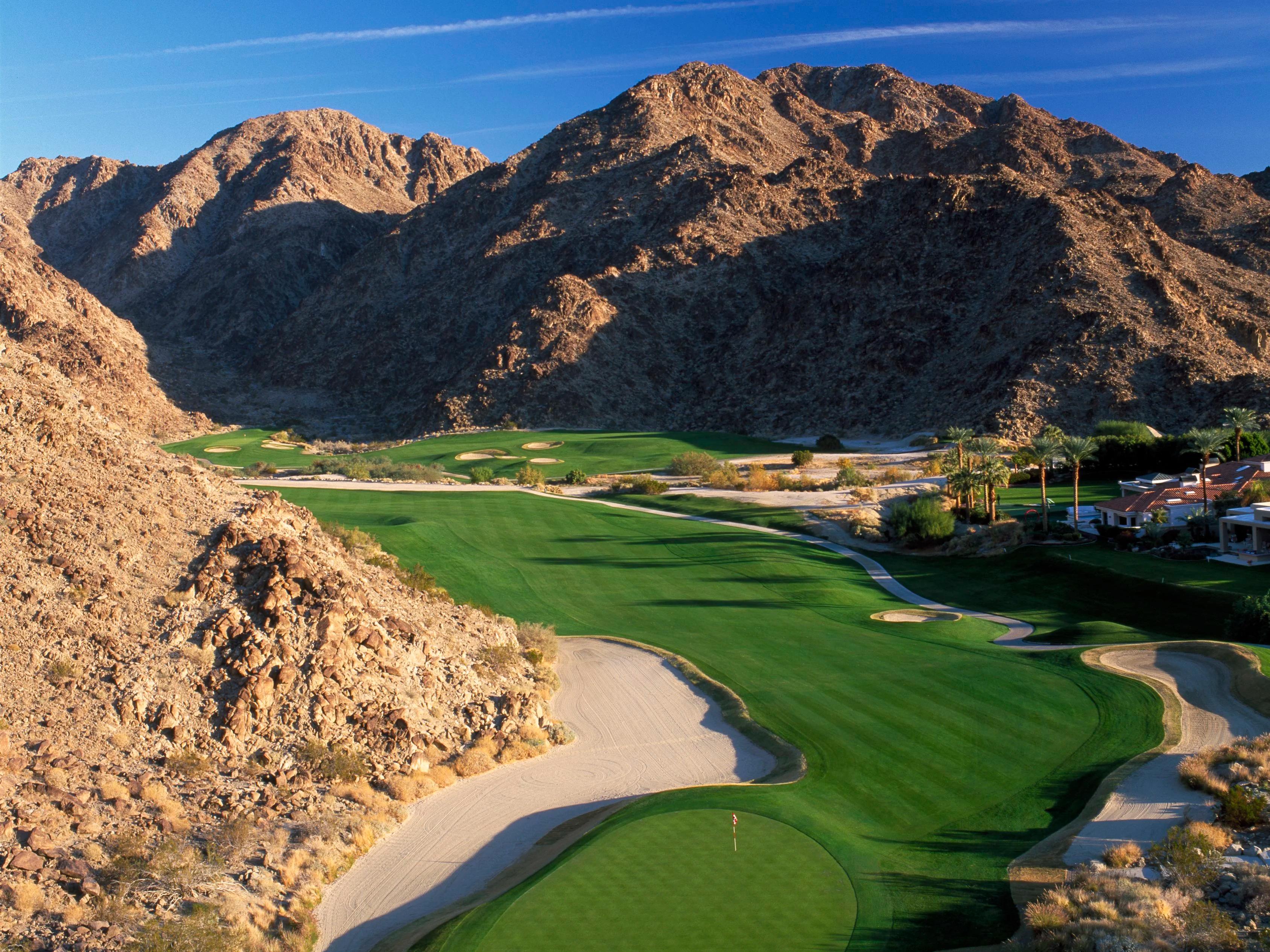 Overhead view of a well maintained fairway leading to a smooth green between mountains