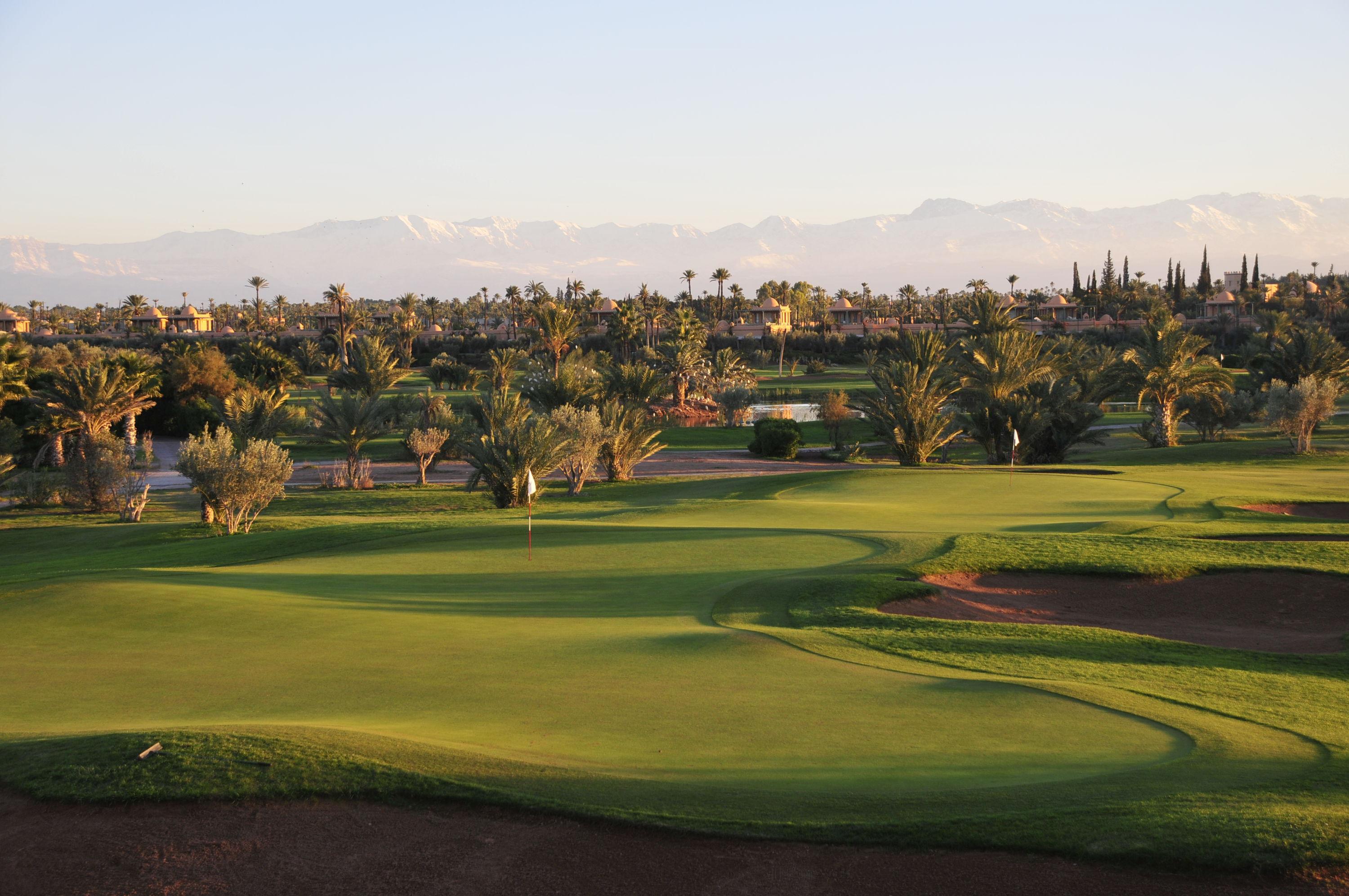 A well maintained fairway nestled with sand bunkers under clear blue skies