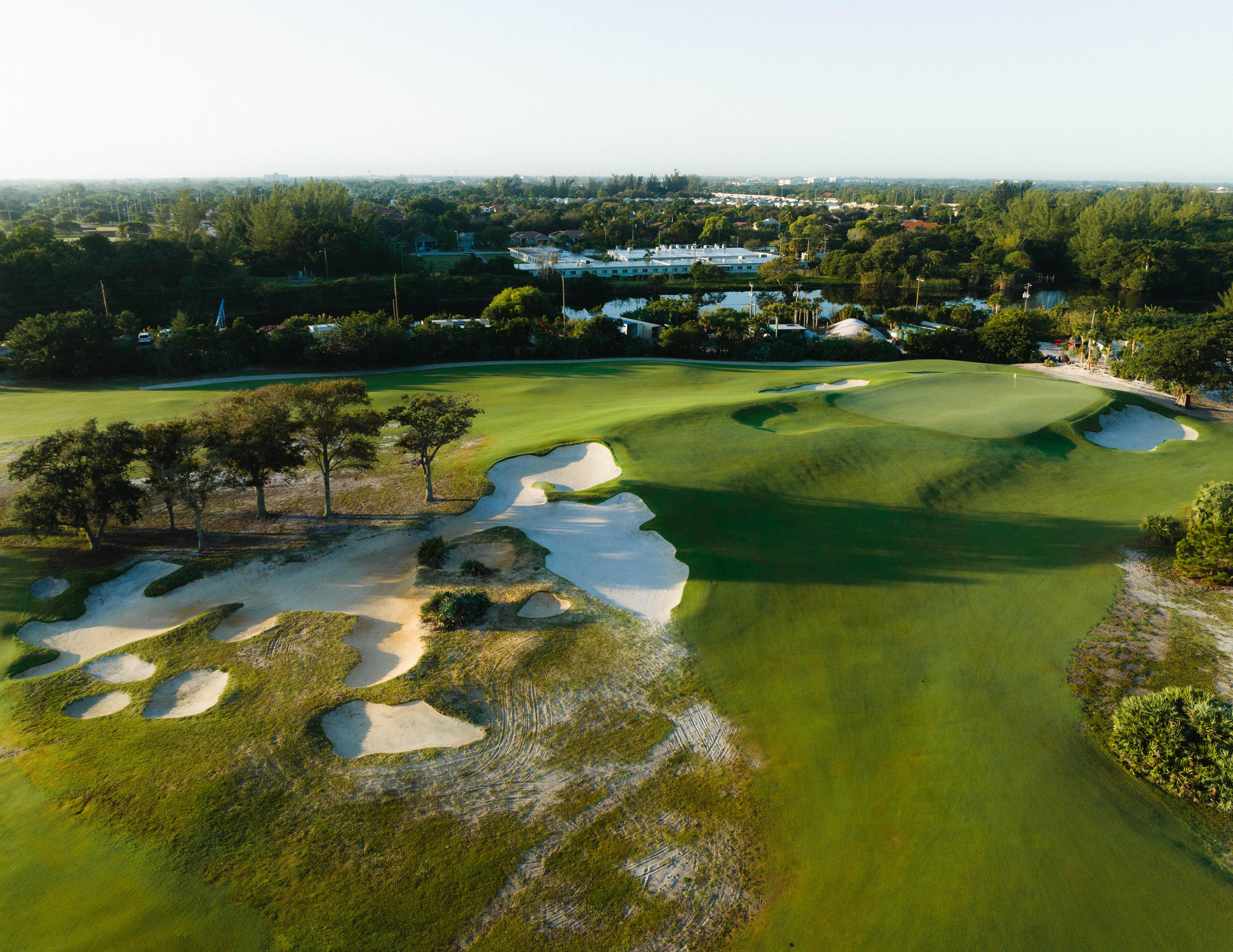 A well maintained fairway nestled with sand bunkers leading to a smooth green
