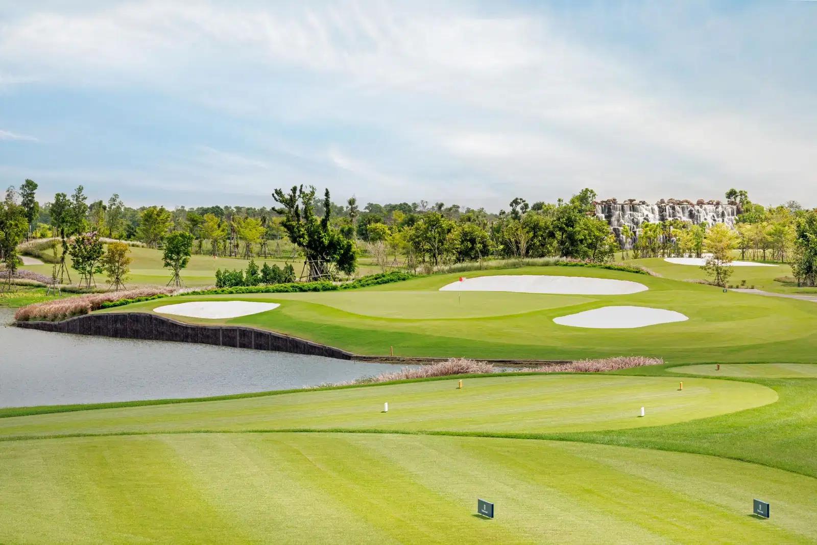 A well maintained fairway nestled with sand bunkers next to a water hazard