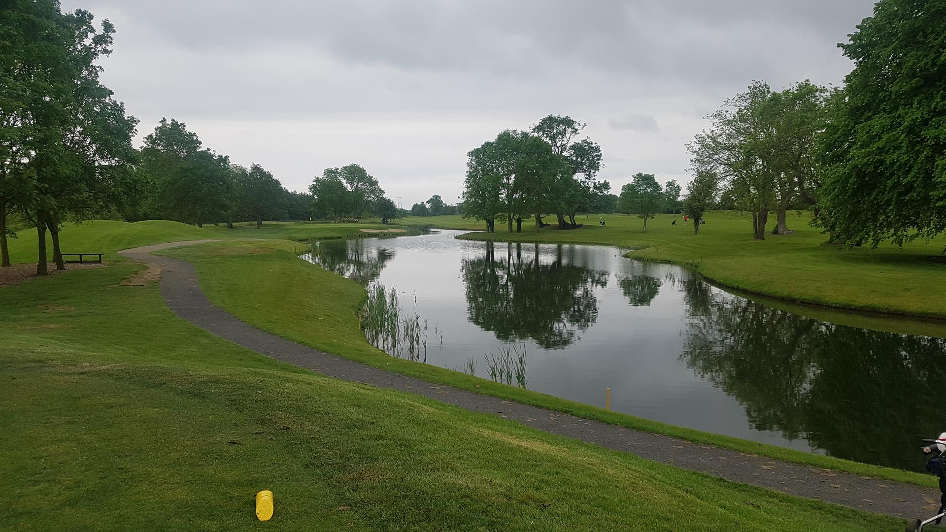 a lake sandwiched by golf greens