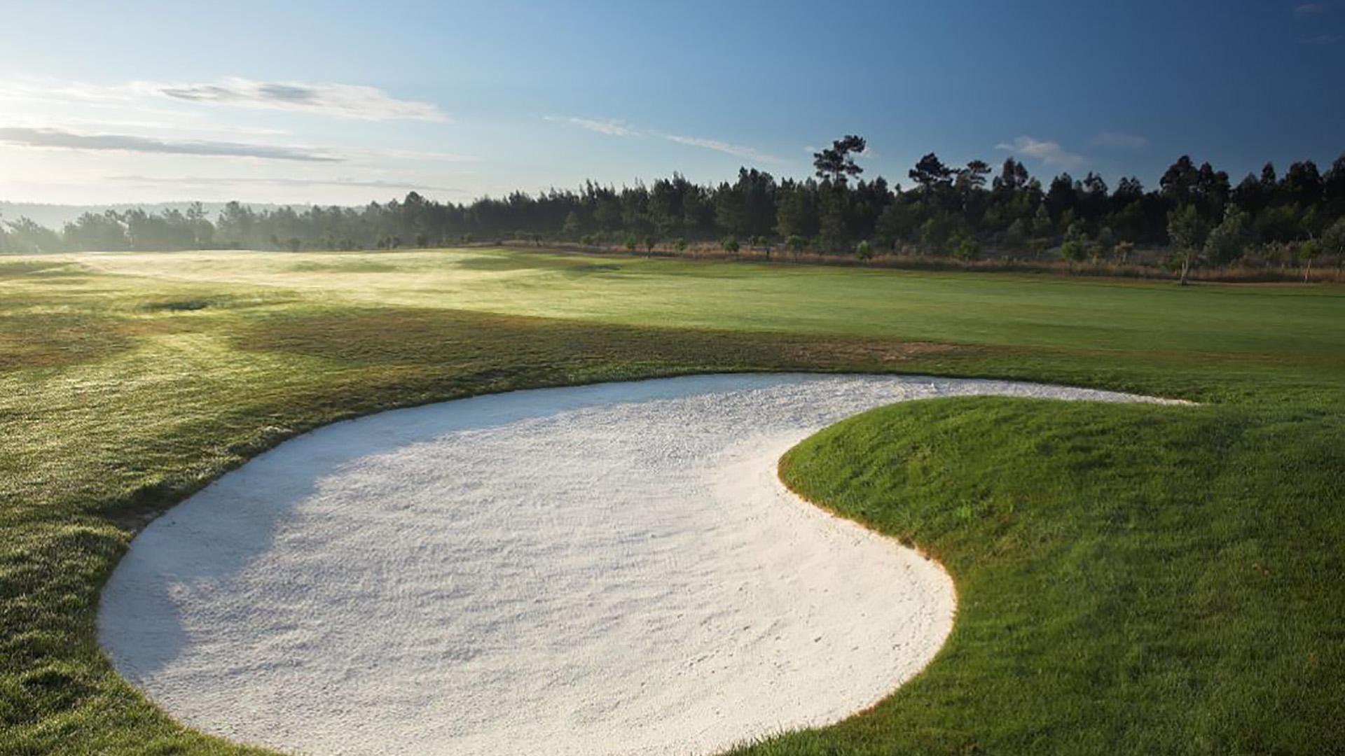A smooth green nestled with a sand bunker at Bom Sucesso Resort
