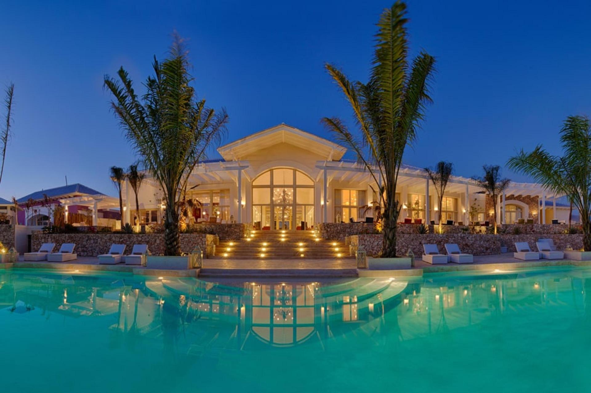 Panoramic view of Eden Roc at Cap Cana lit up at night overlooking the outdoor pool