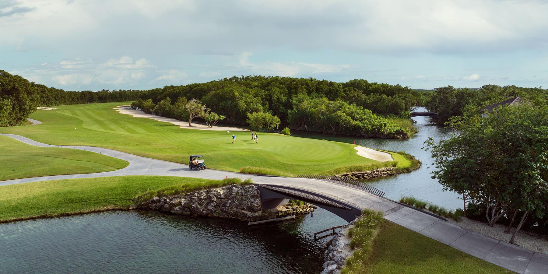 A well maintained fairway with a bridge to navigate the water hazard