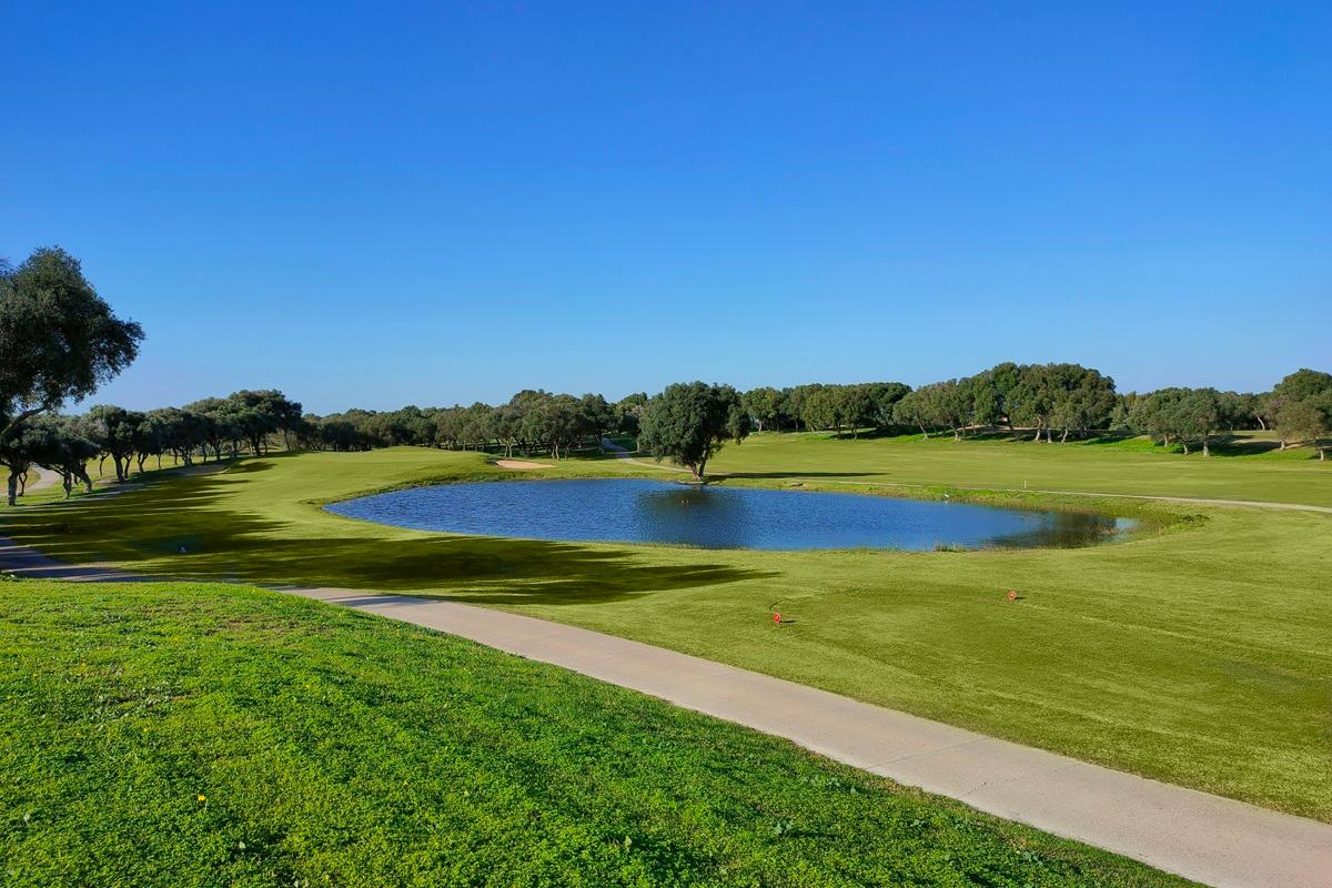 A well maintained fairway with a large water hazard