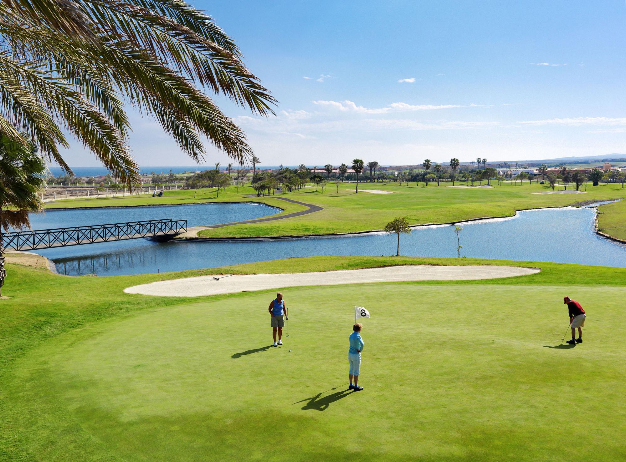 Golfers on a smooth green next to a sand bunker