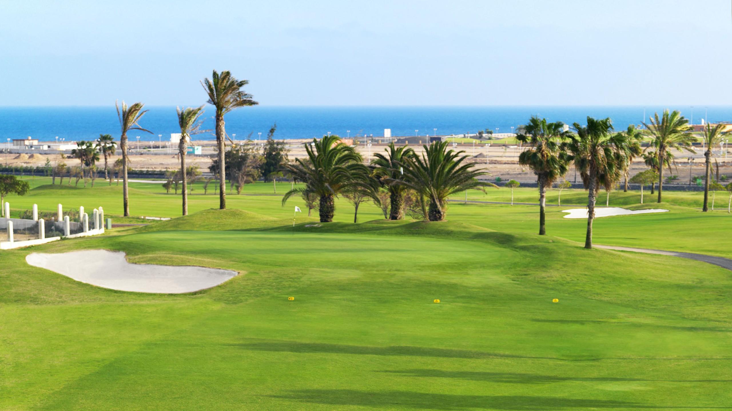A well maintained fairway leading to a smooth green next to a large sand bunker