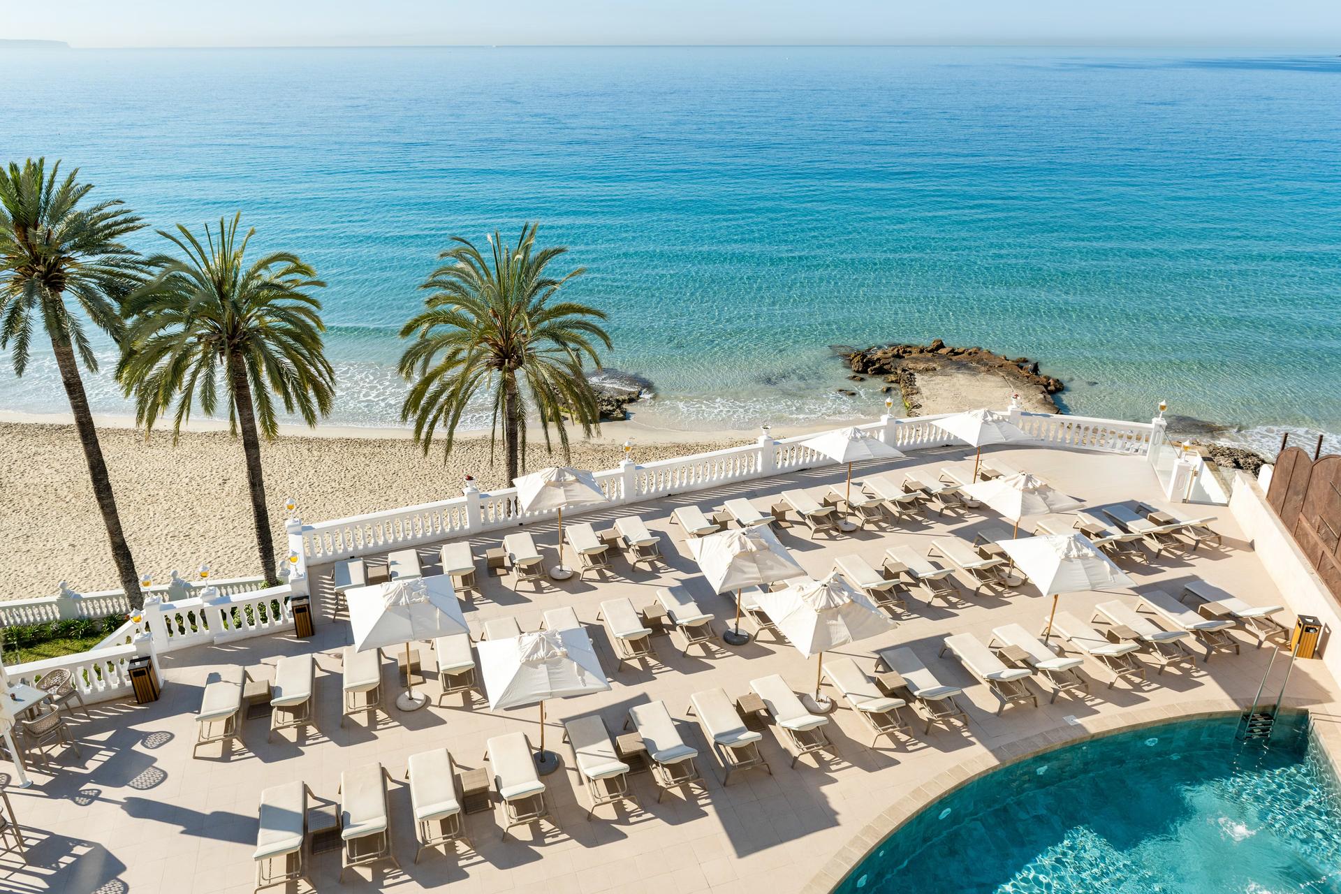 Overhead view of poolside sunbeds with views of the ocean