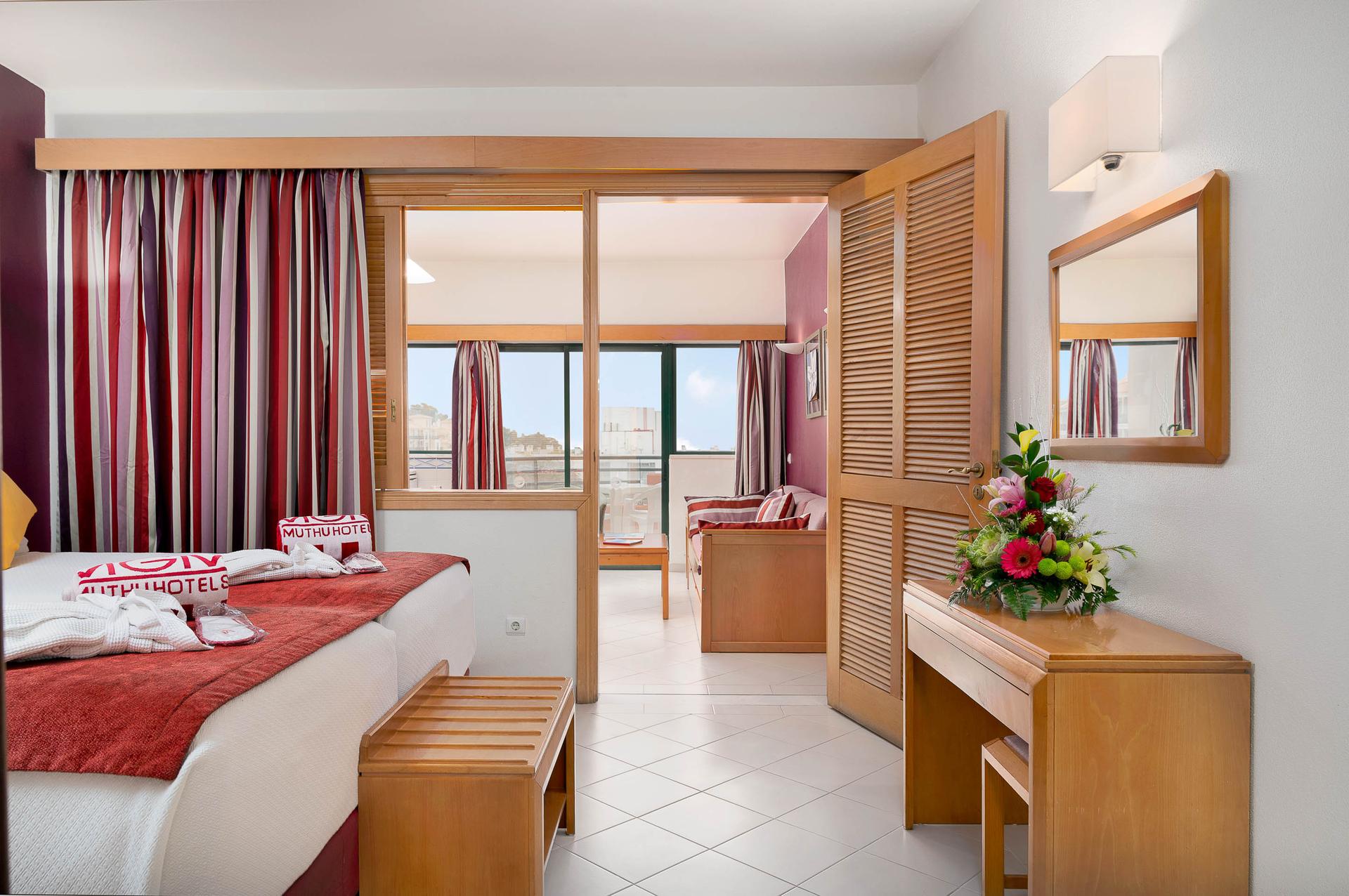 Double bed suite leading towards a living room space and balcony at Muthu Forte da Oura