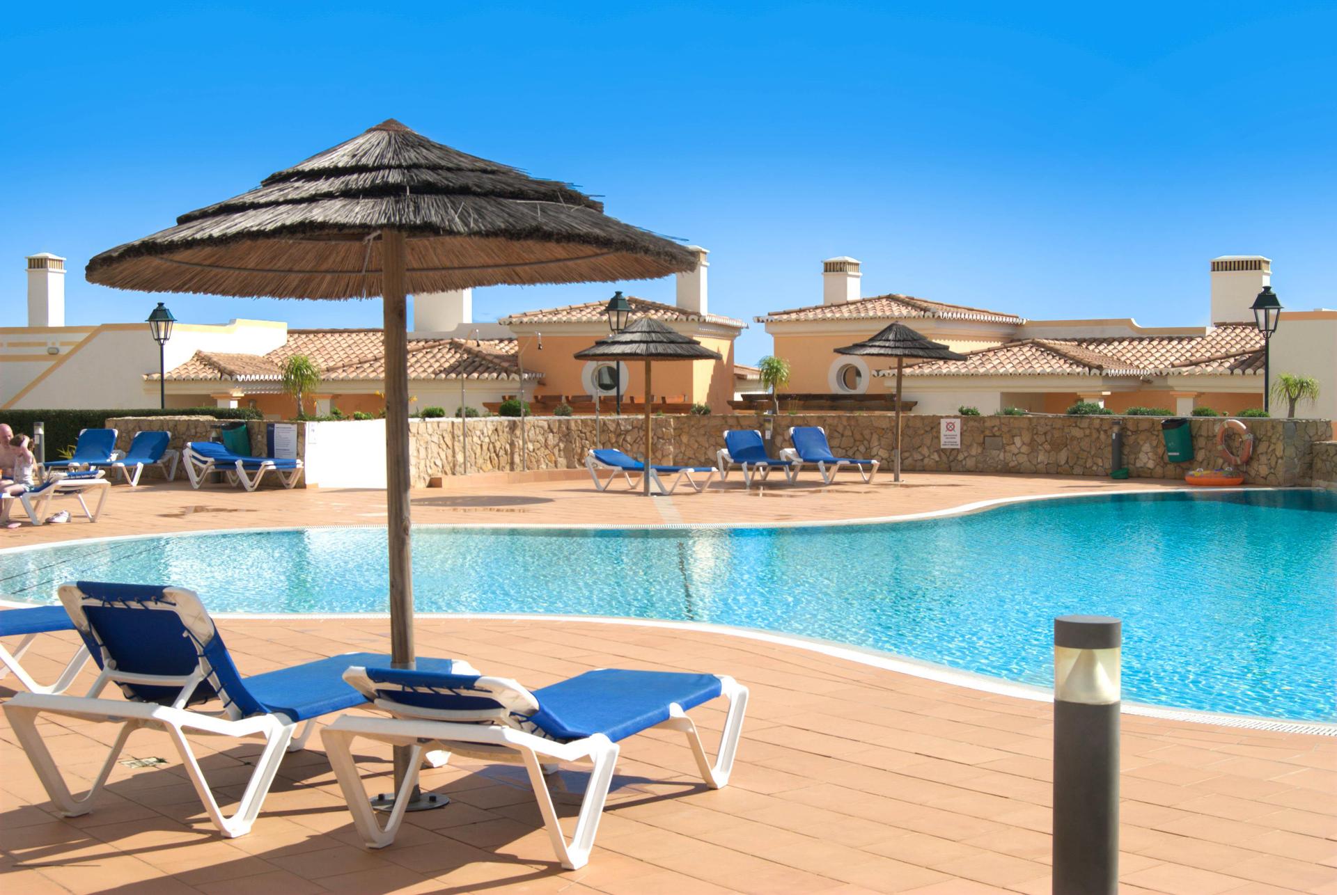 Outdoor pool at Salema Beach Village lined with sunbeds