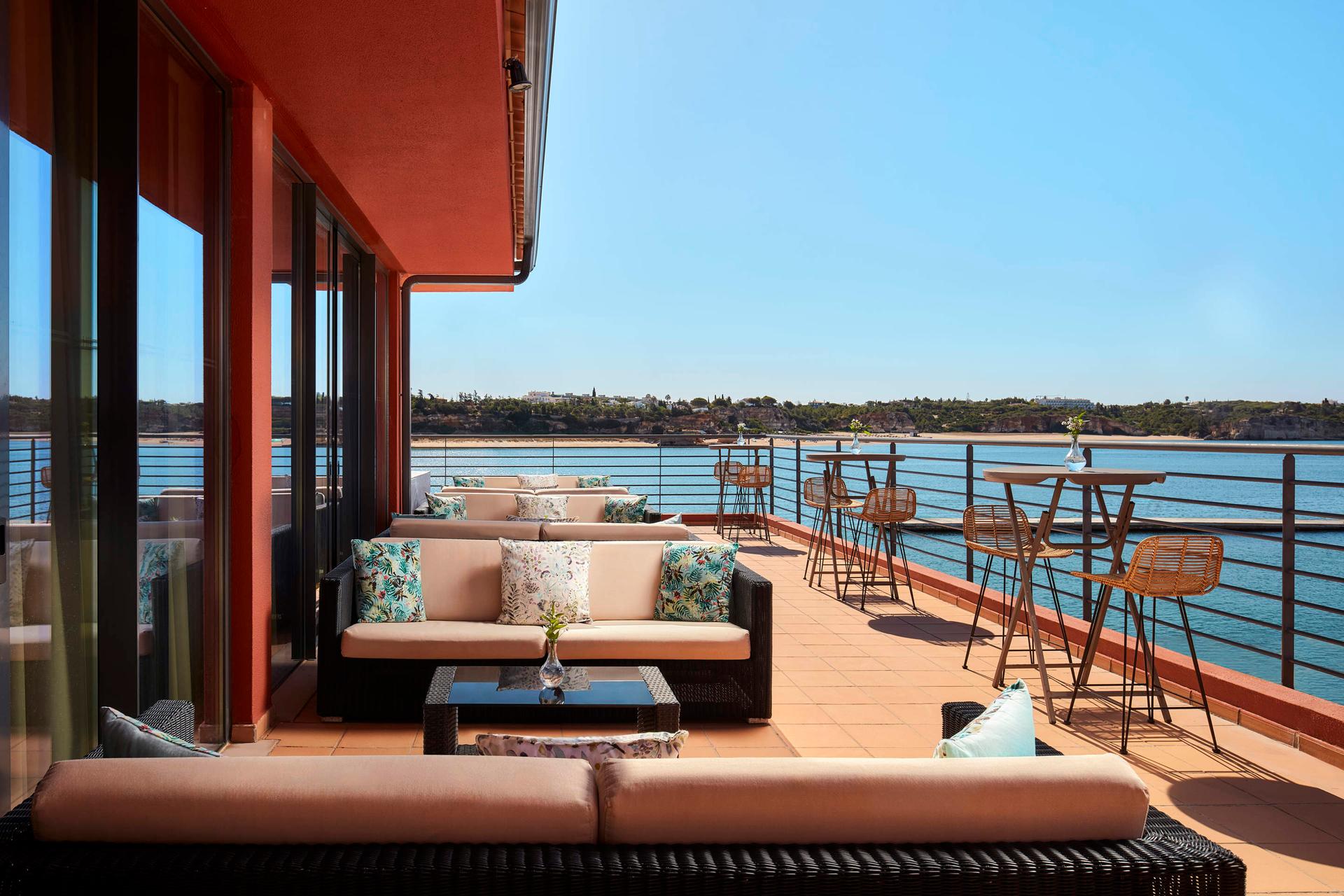 Rooftop lounging area nestled with sofas and dining tables at NH Marina Portimão