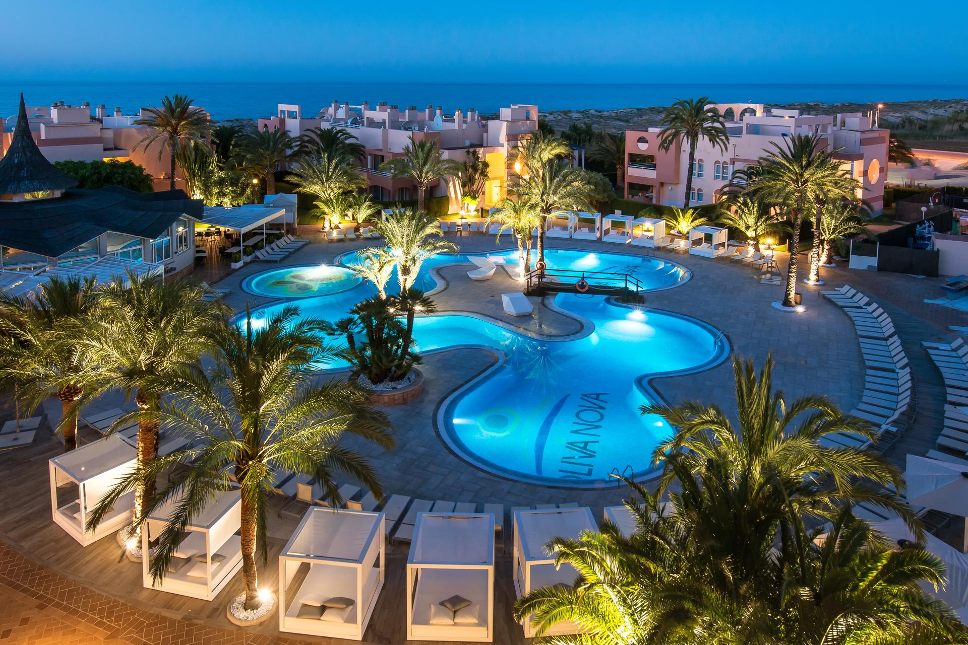 Overhead view of the outdoor swimming pool at Oliva Nova Beach & Golf Hotel lit up at evening
