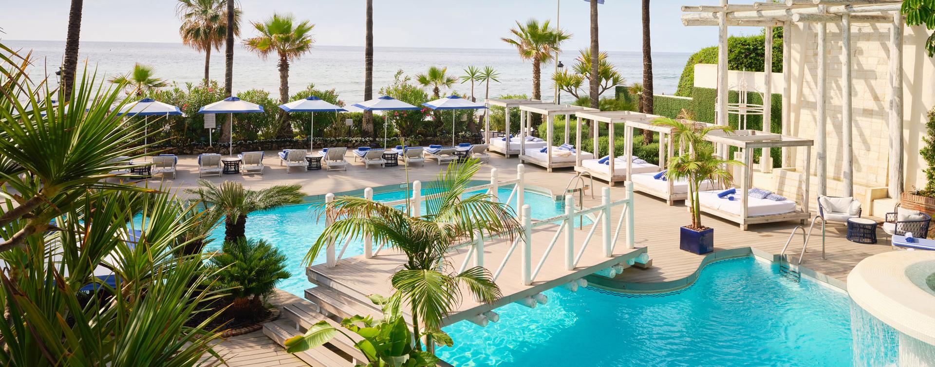 Outdoor swimming pool with a bridge to navigate the resort at Puente Romano Beach Resort