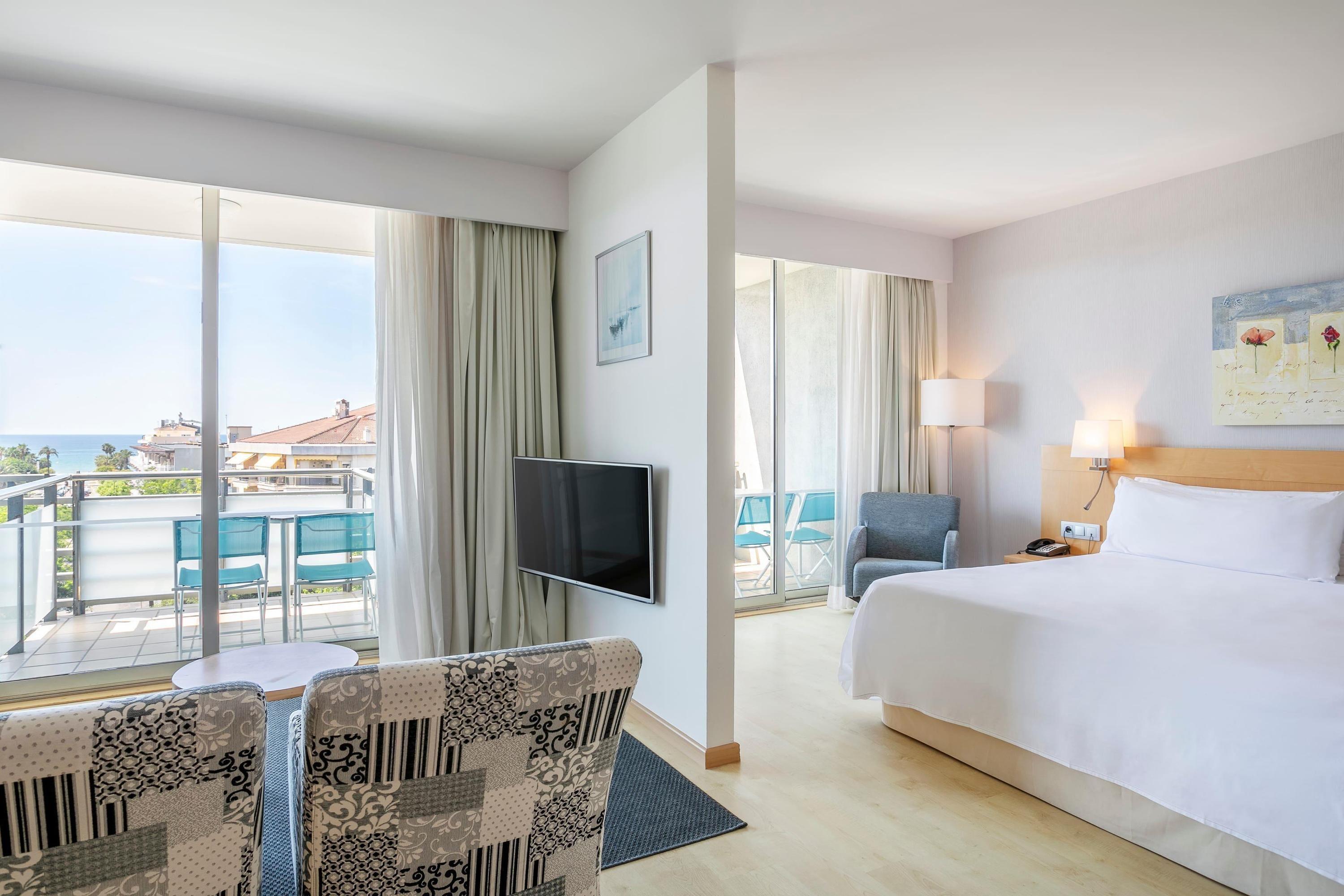Double bed suite with separate living room area and balcony at Sol Port Cambrils Hotel