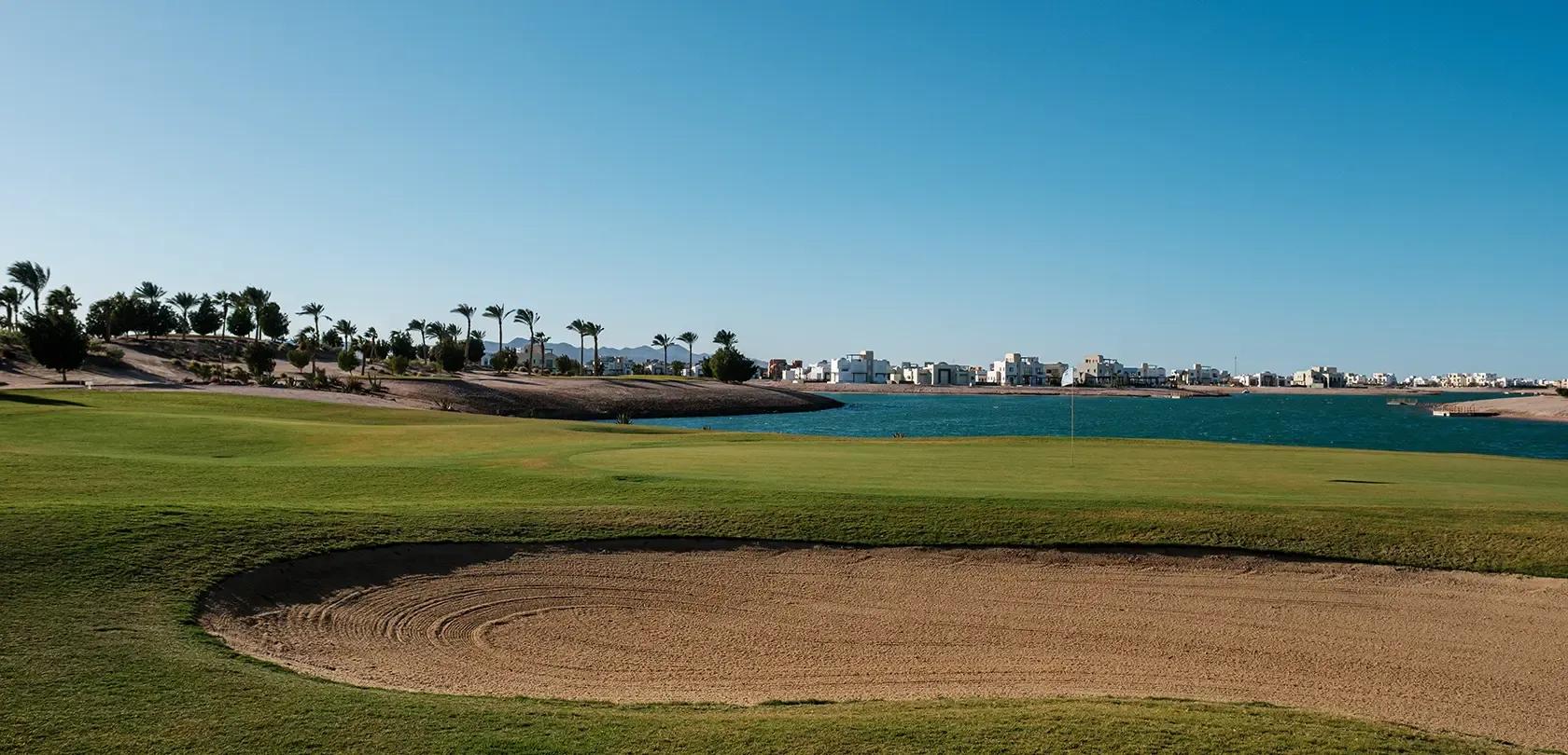 A well maintaiined fairway sandwiched by a water hazard and sand bunker