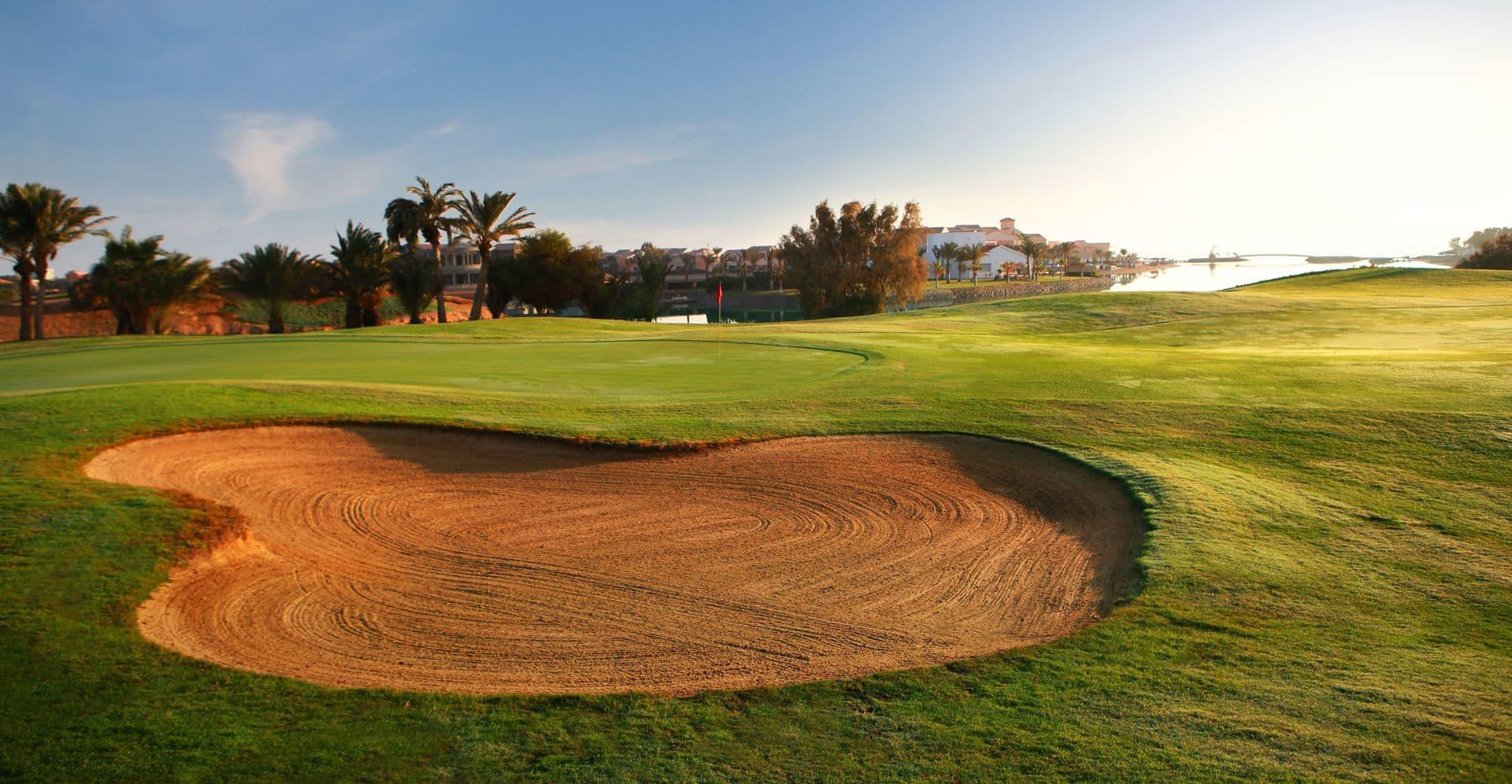 A large sand bunker on a well maintained fairway