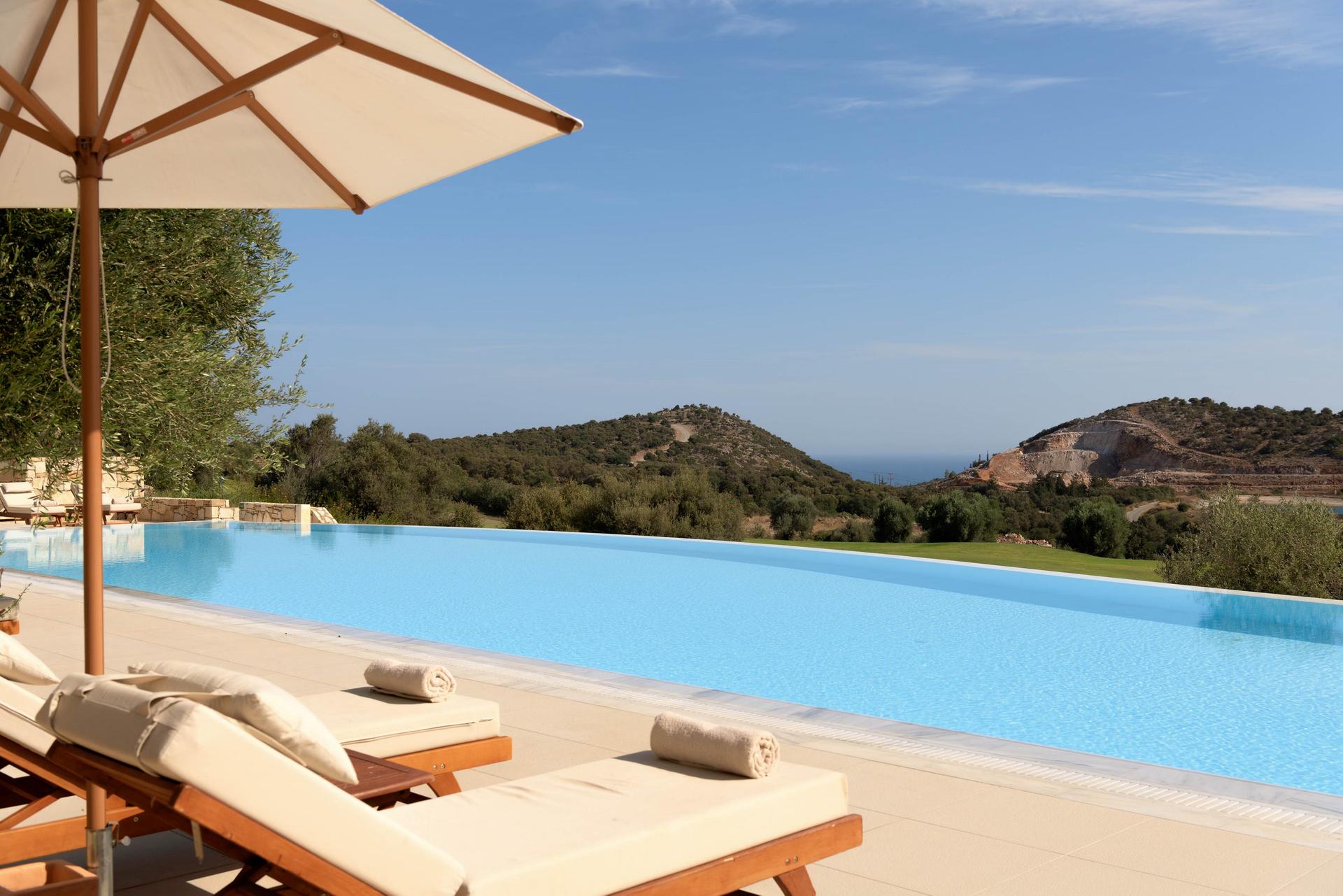 Outdoor swimming pool lined with sunbeds at Crete Golf Club & Hotel