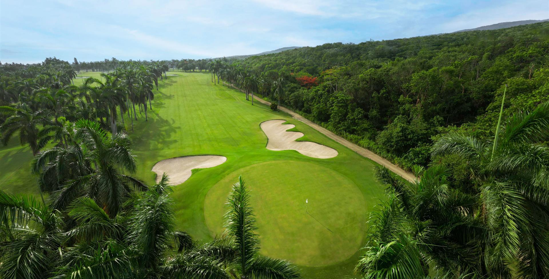 Overhead view of a well maintained fairway leading to a smooth green surrounded by sand bunkers