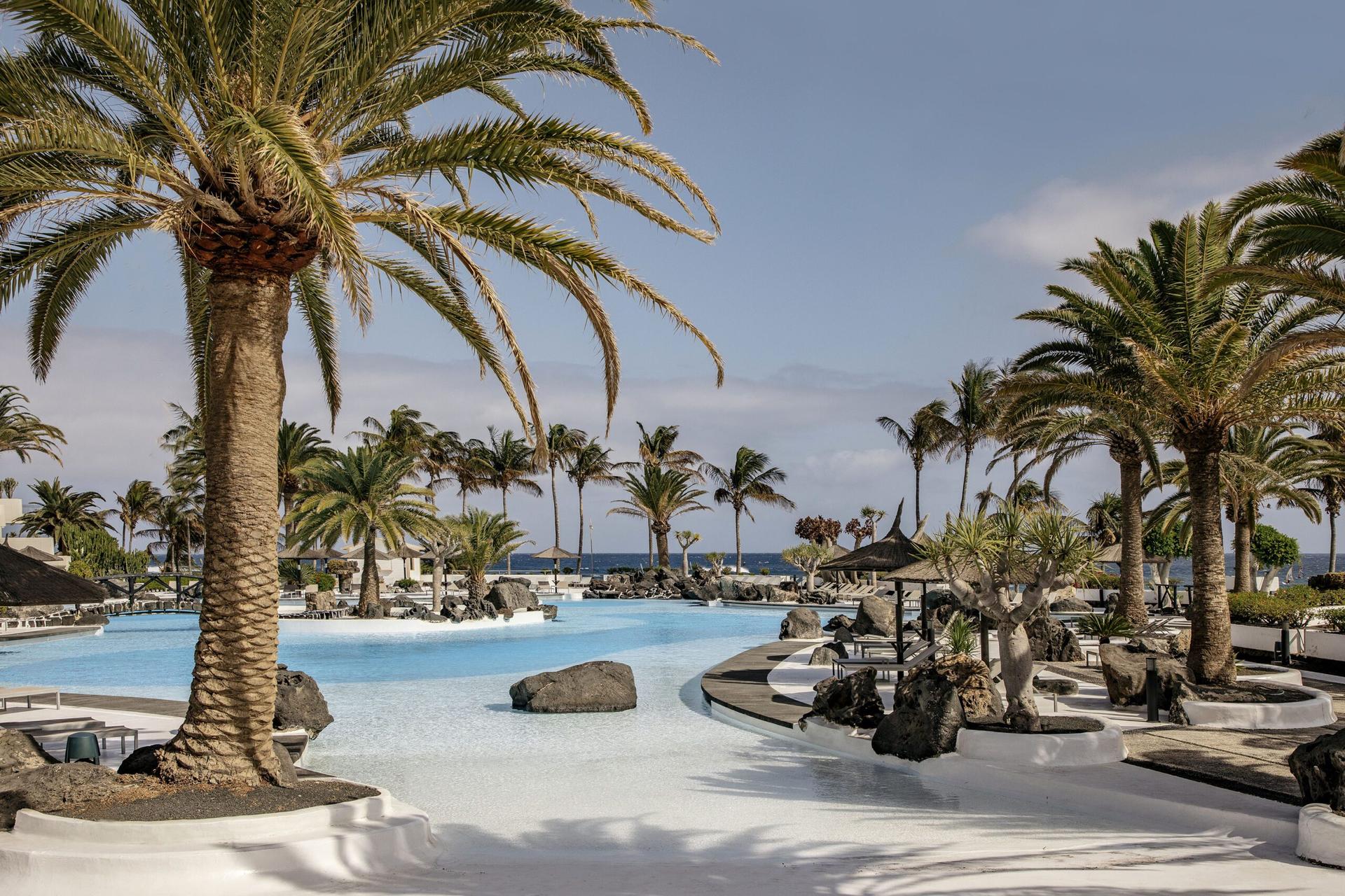 Outdoor swimming pool lined with palm trees at Paradisus Salinas Lanzarote