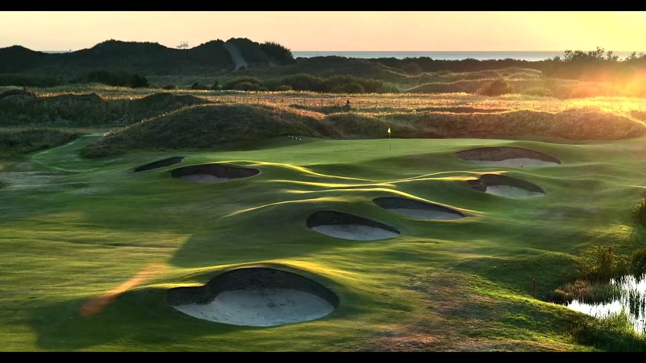 A well maintained fairway nestled with sand bunkers under sunset