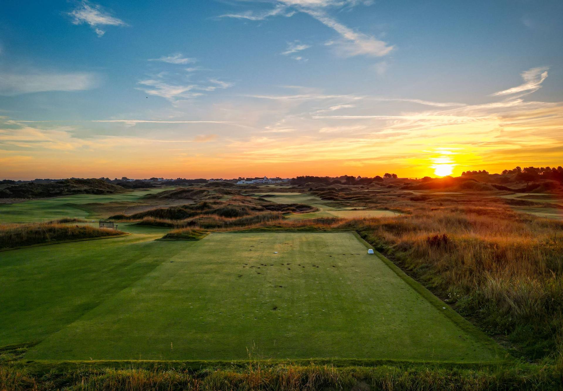 A tee box with the sun shining in the distance