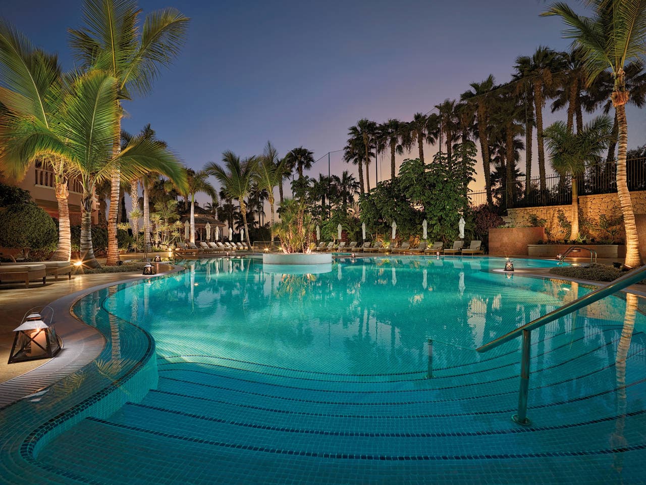 Outdoor pool area surrounded by palm trees
