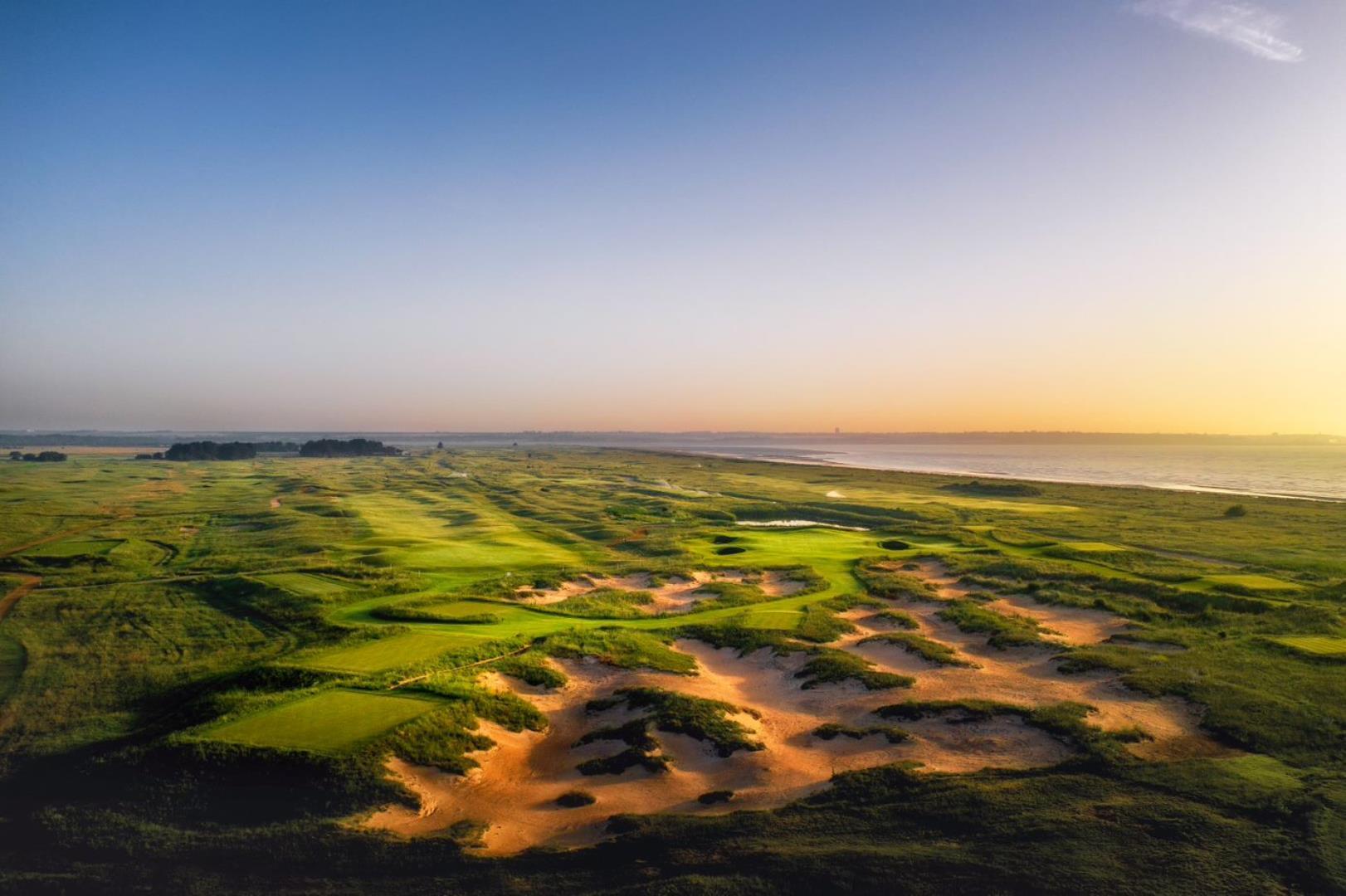 Aerial view of a well maintained fairway surrounded by a sandy rough