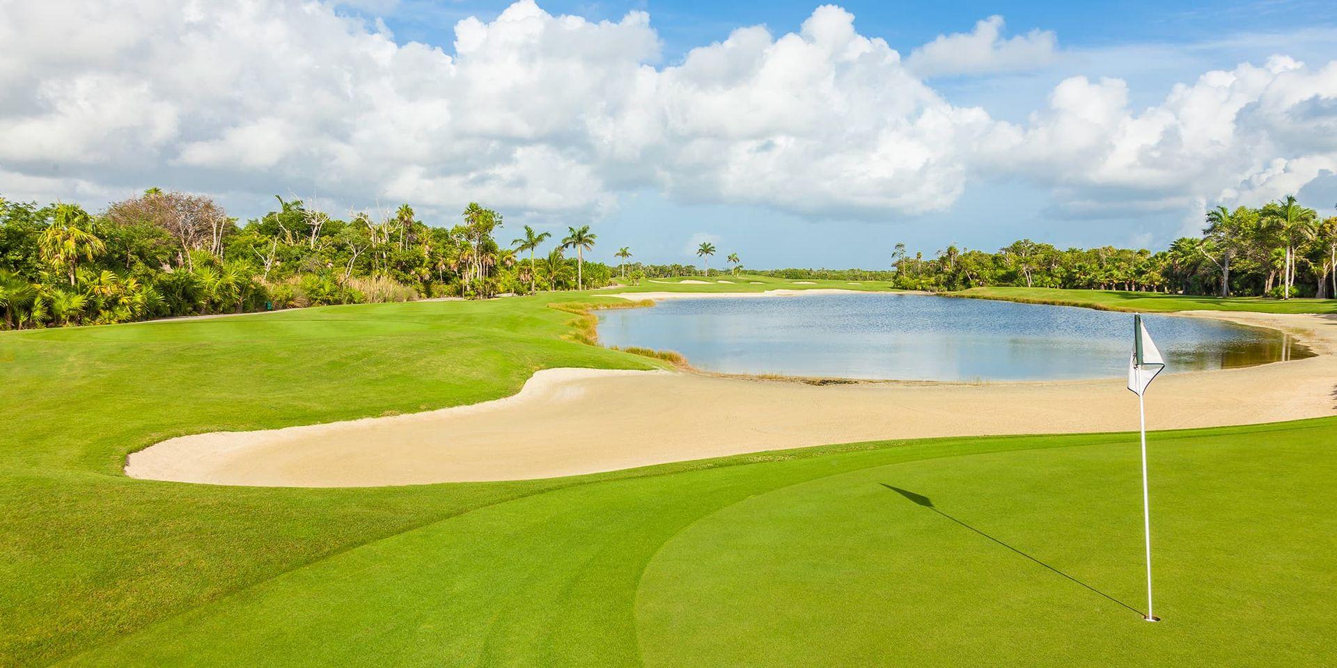 A smooth green next to a sand bunker and water hazard