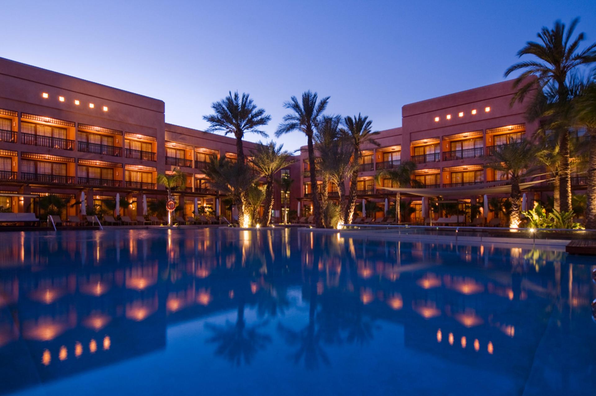 Panoramic view of the Hotel du Golf by Pickalbatros building overlooking the outdoor poo at evening