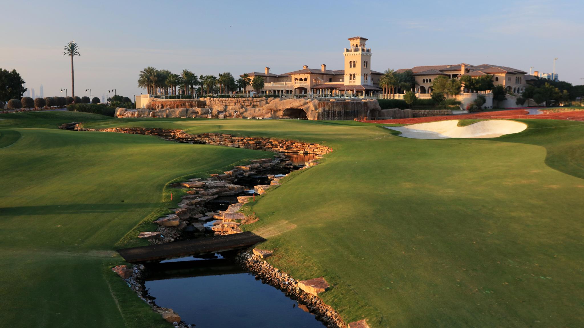 A well maintained fairway with a water hazard leading towards the clubhouse