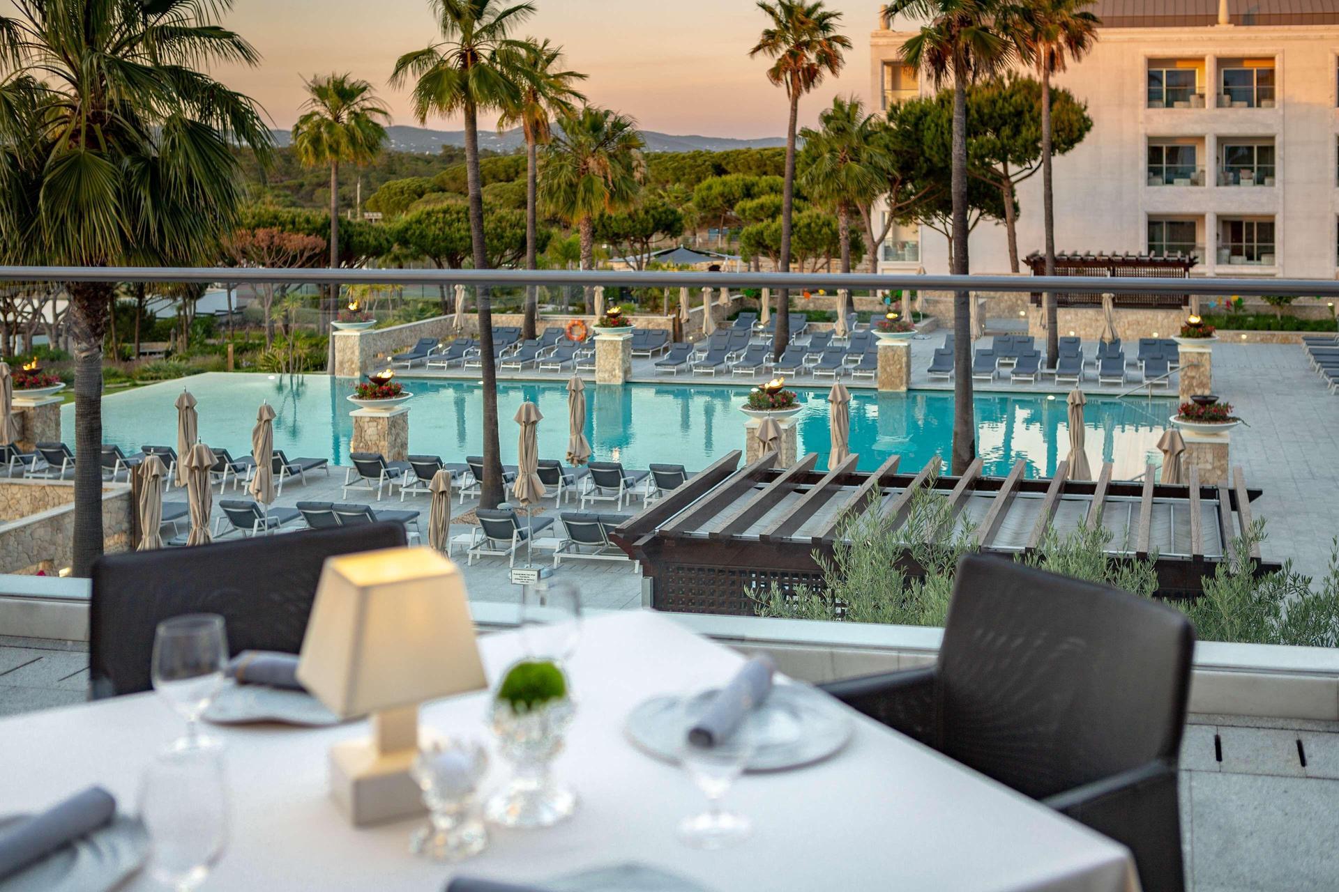 View of outdoor swimming pool from a balcony dining area
