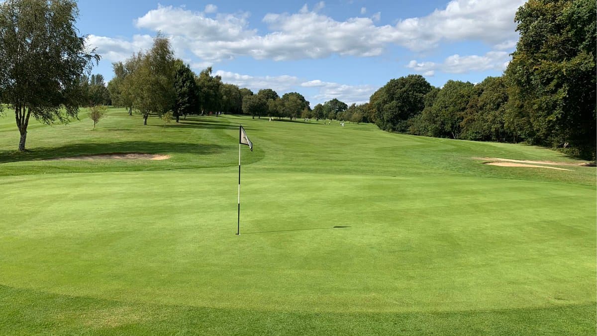 Smooth, manicured green with narrow fairway behind