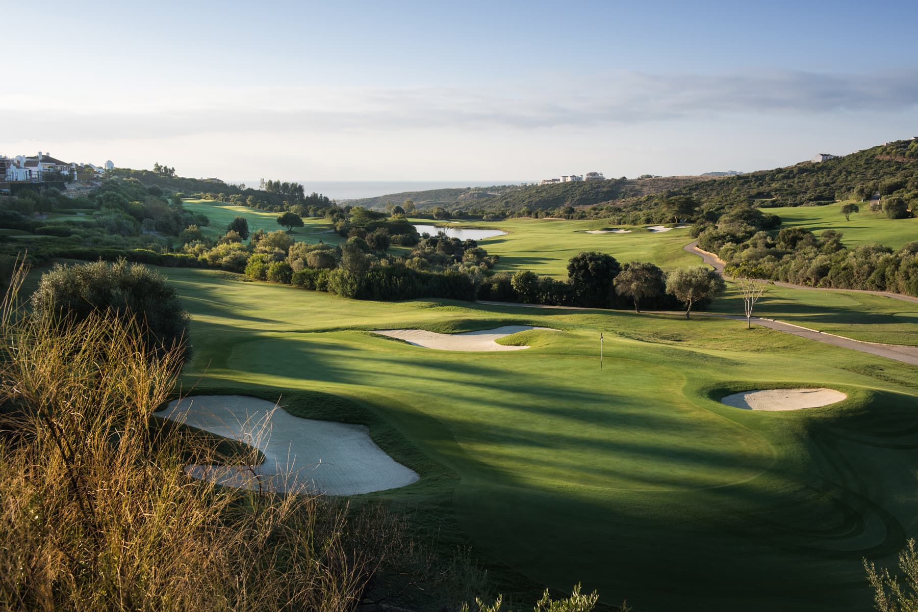 A well maintained fairway leading to a smooth green surrounded by sand bunkers