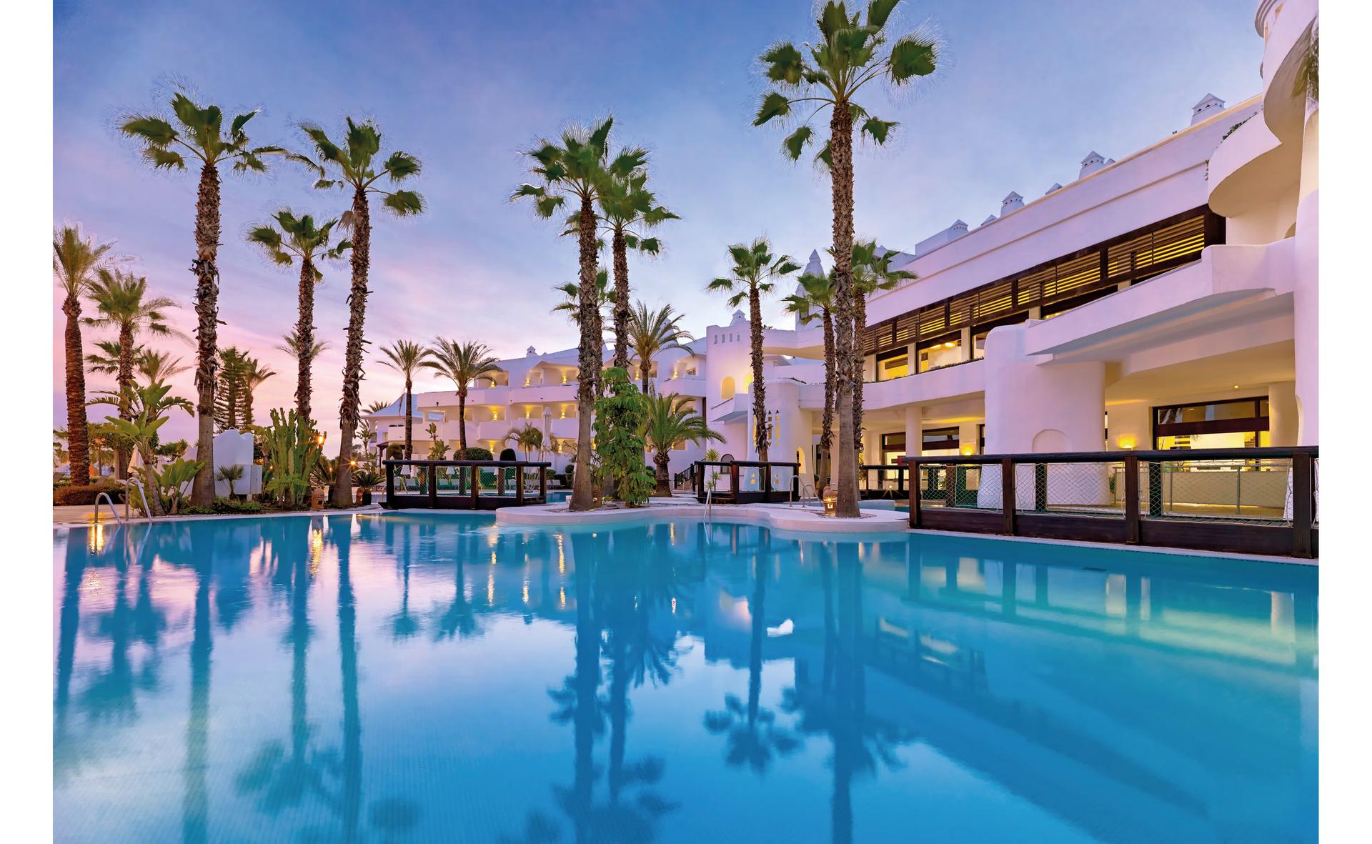 Outdoor swimming pool surrounded by palm trees at H10 Estepona Palace