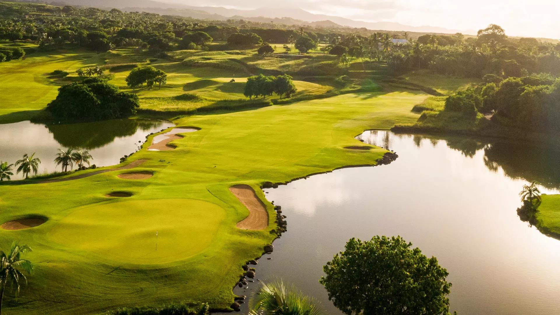 A manicured fairway with sand bunkers sandwiched by two water hazards