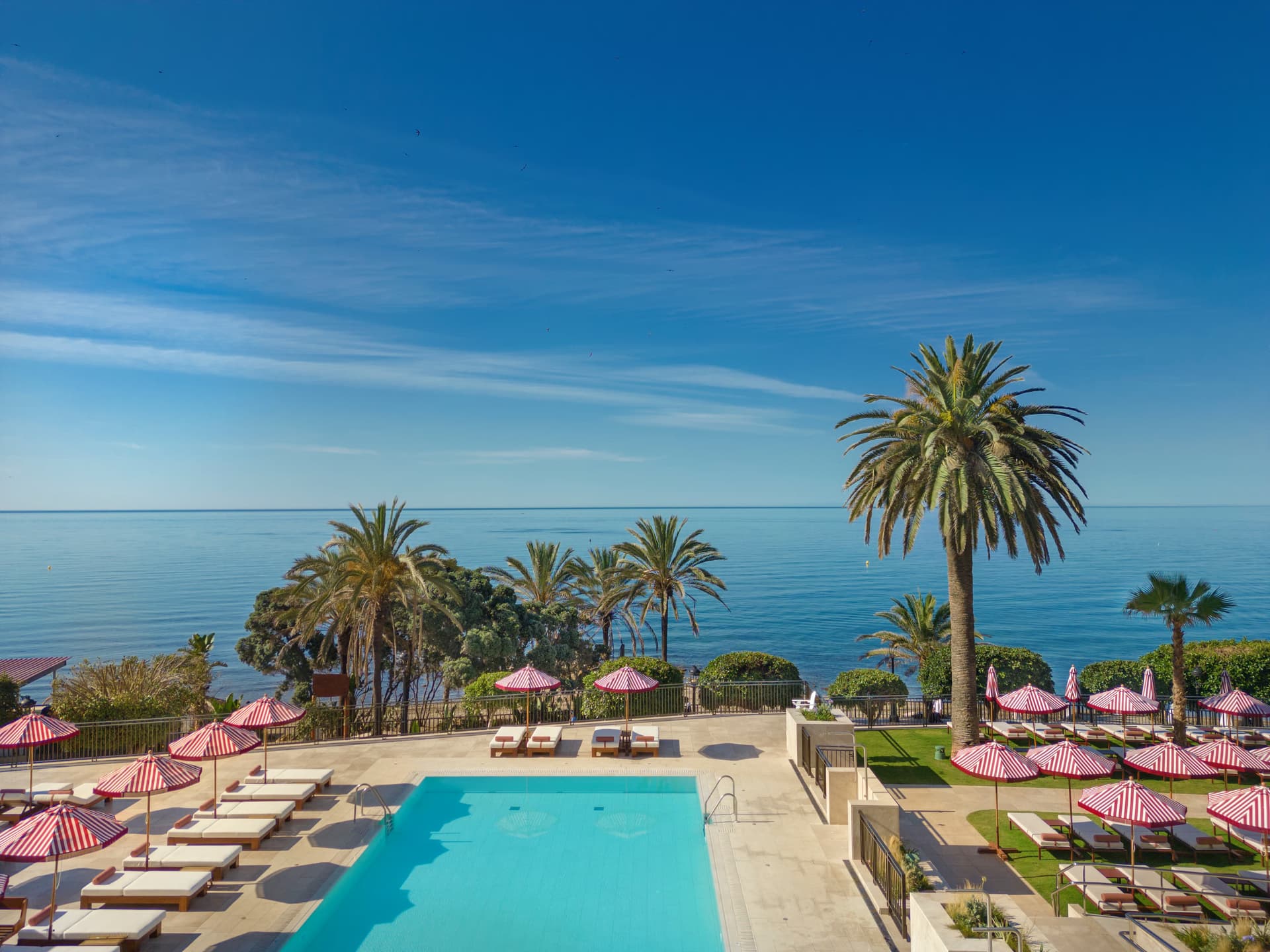 Outdoor swimming pool surrounded by sunbeds at Hotel El Fuerte Marbella