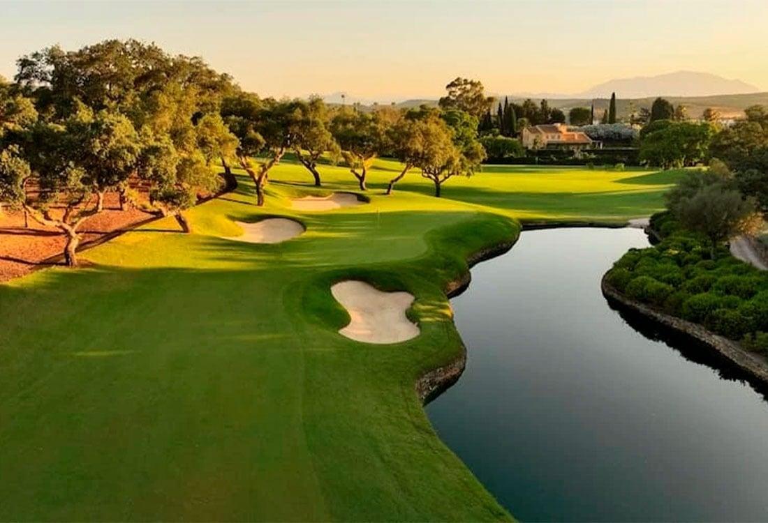 A well maintained fairway nestled with sand bunkers next to a water hazard
