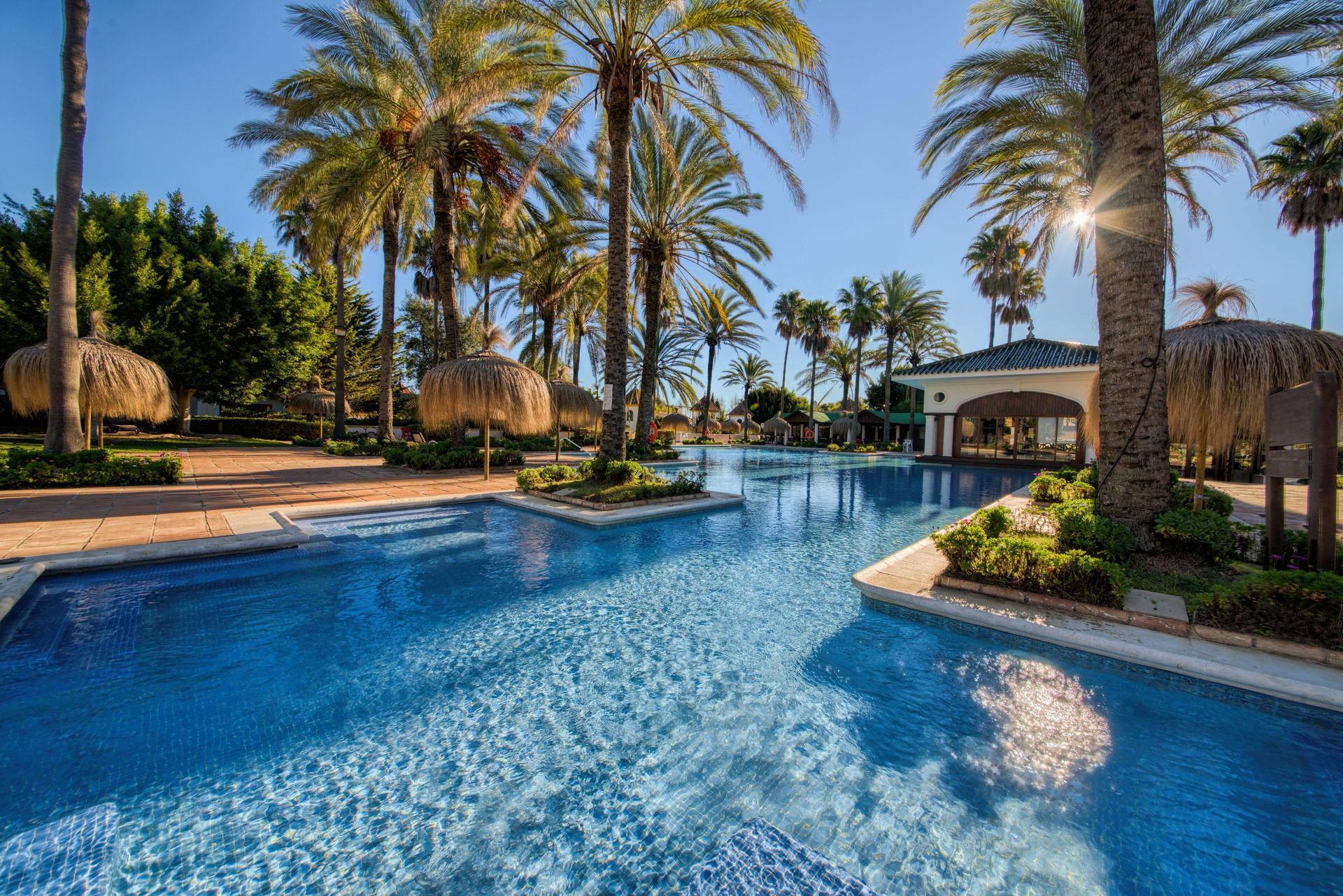 Outdoor swimming pool surrounded by palm trees at Inmood San Roque Hotel Sotogrande