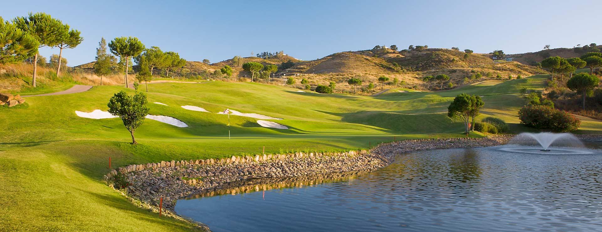 Panoramic view of a well maintained fairway nestled with sand bunkers running besides a water hazard