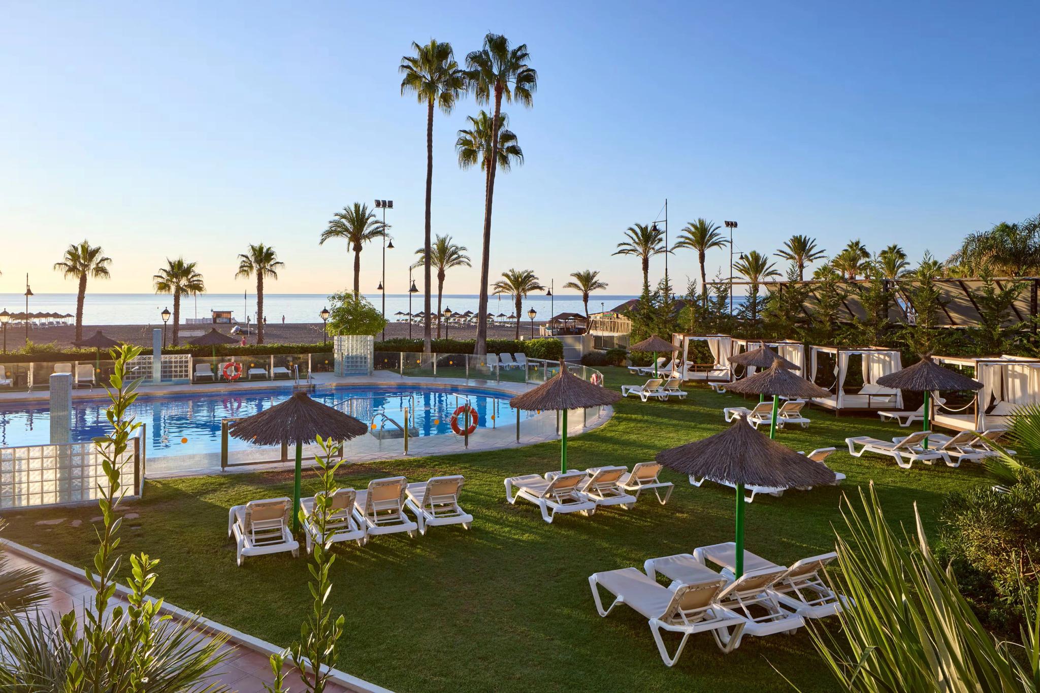 Panoramic view of the Melia Sol Principe outdoor swimming pool nestled with palm trees and sunbeds