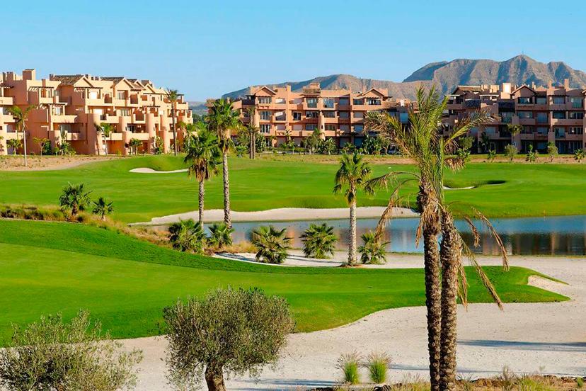 Large bunkers in the foreground with a winding fairway around a water hazard with the hotel in the background