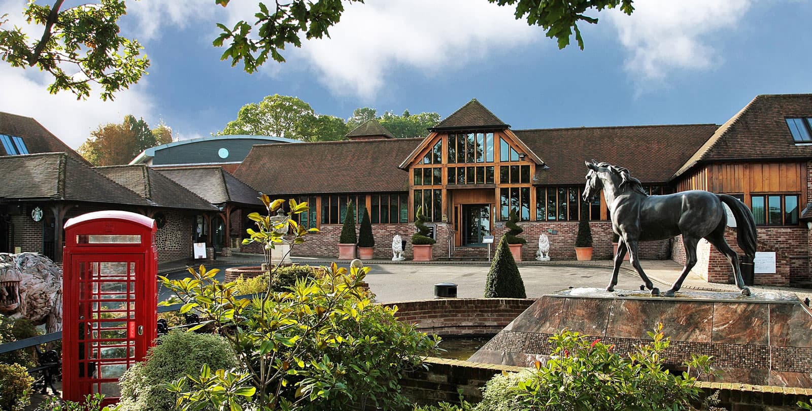 Front entrance of the resort with a horse statue fountain and red phonebox in view