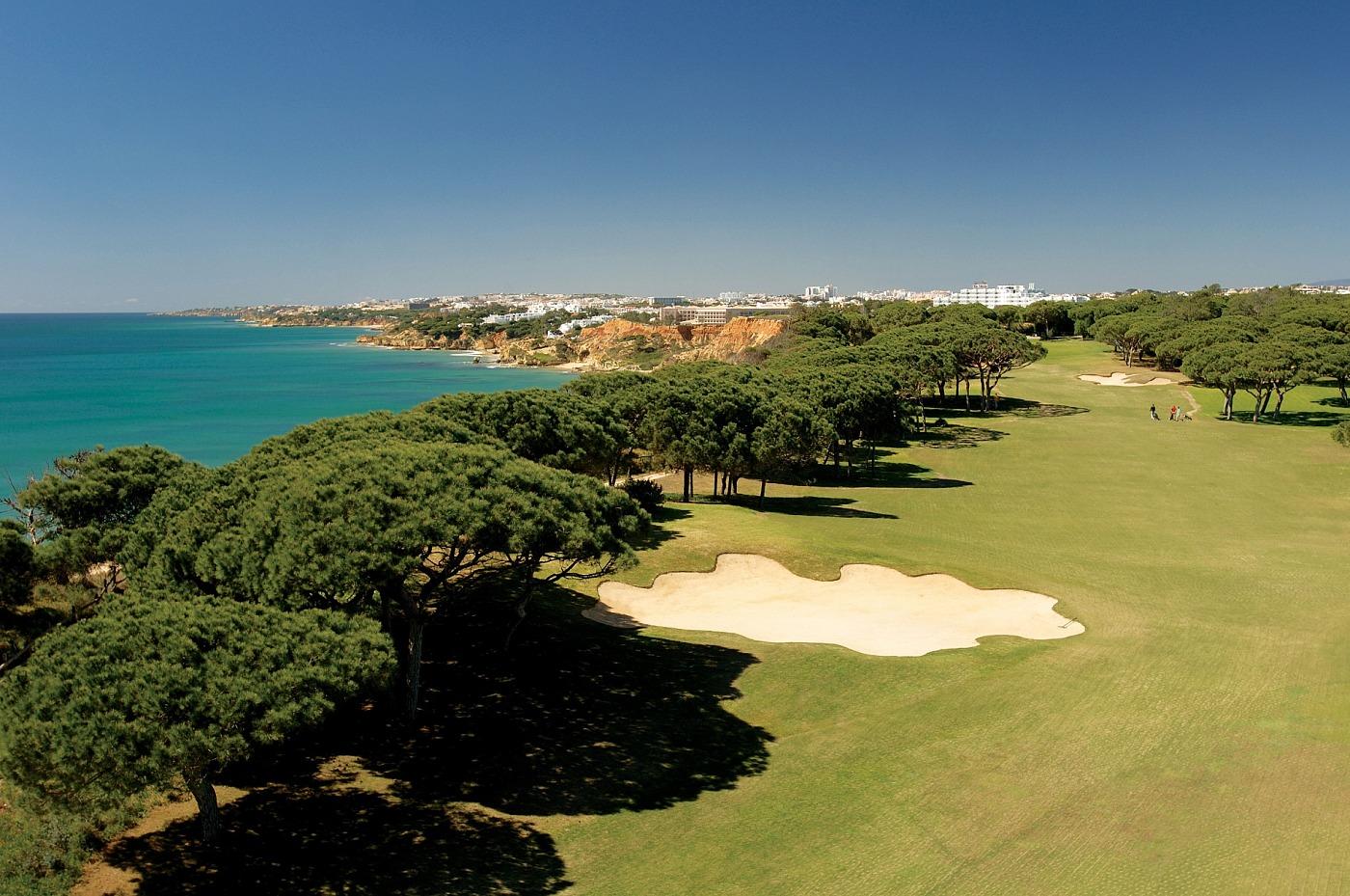 A well maintained fairway with a sand bunker and coastal views