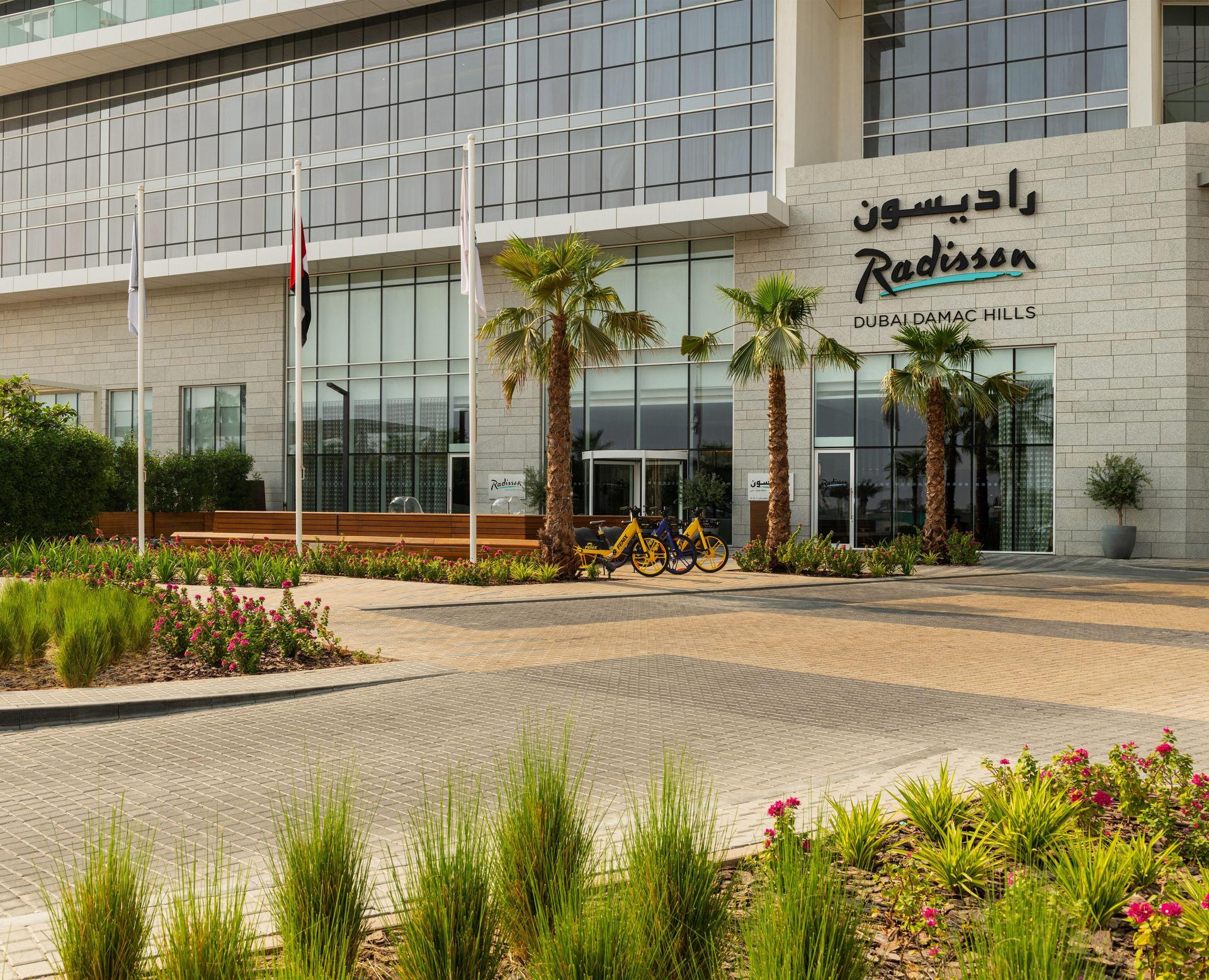 Front entrance to the Radisson Dubai Damac Hills with palm trees