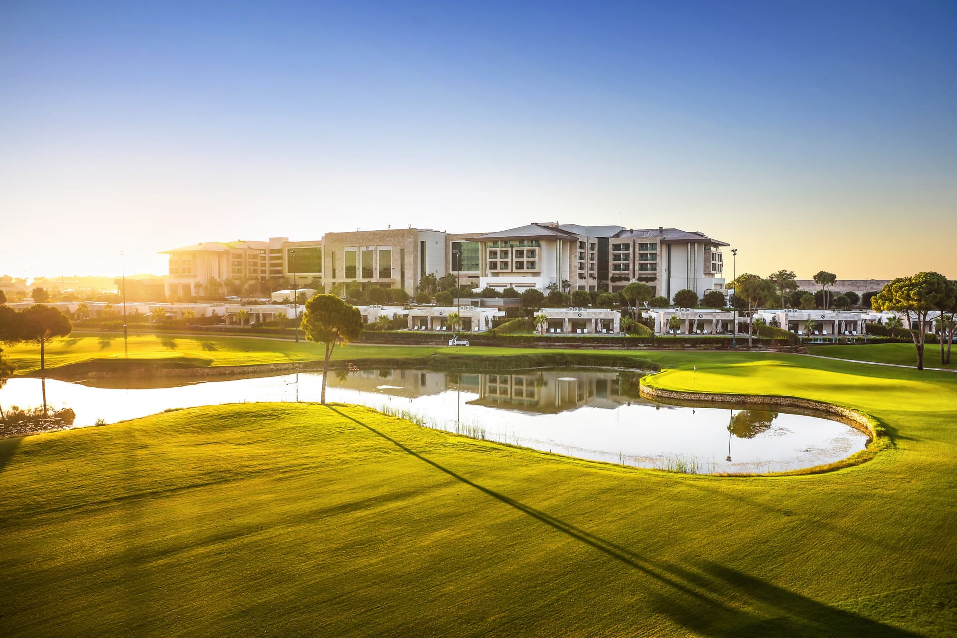 A well maintained fairway next to a water hazard under the sun
