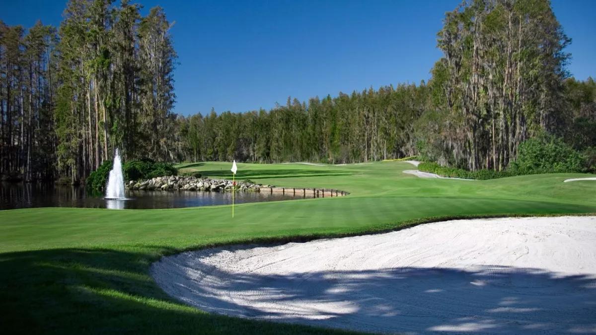 A well maintained fairway leading to a smooth green sandwiched by a water hazard and sand bunker