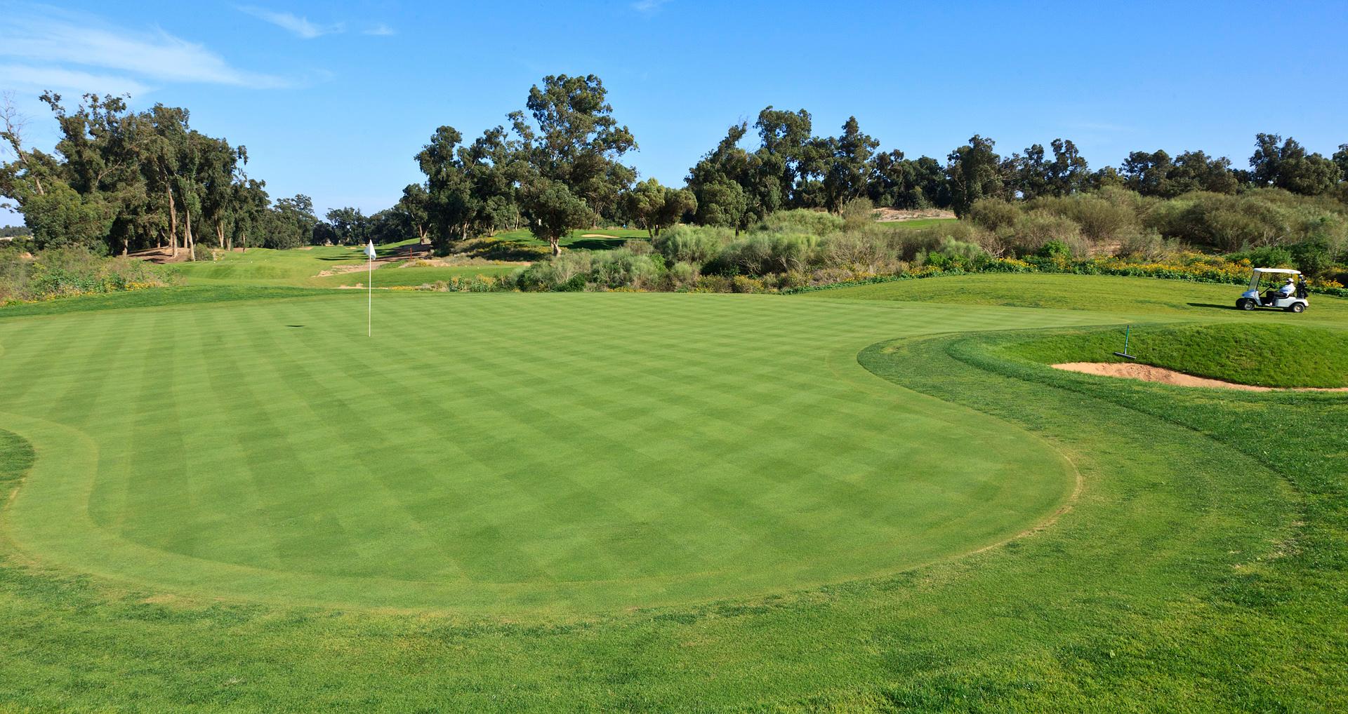A well maintained water hazard nestled with a sand bunker