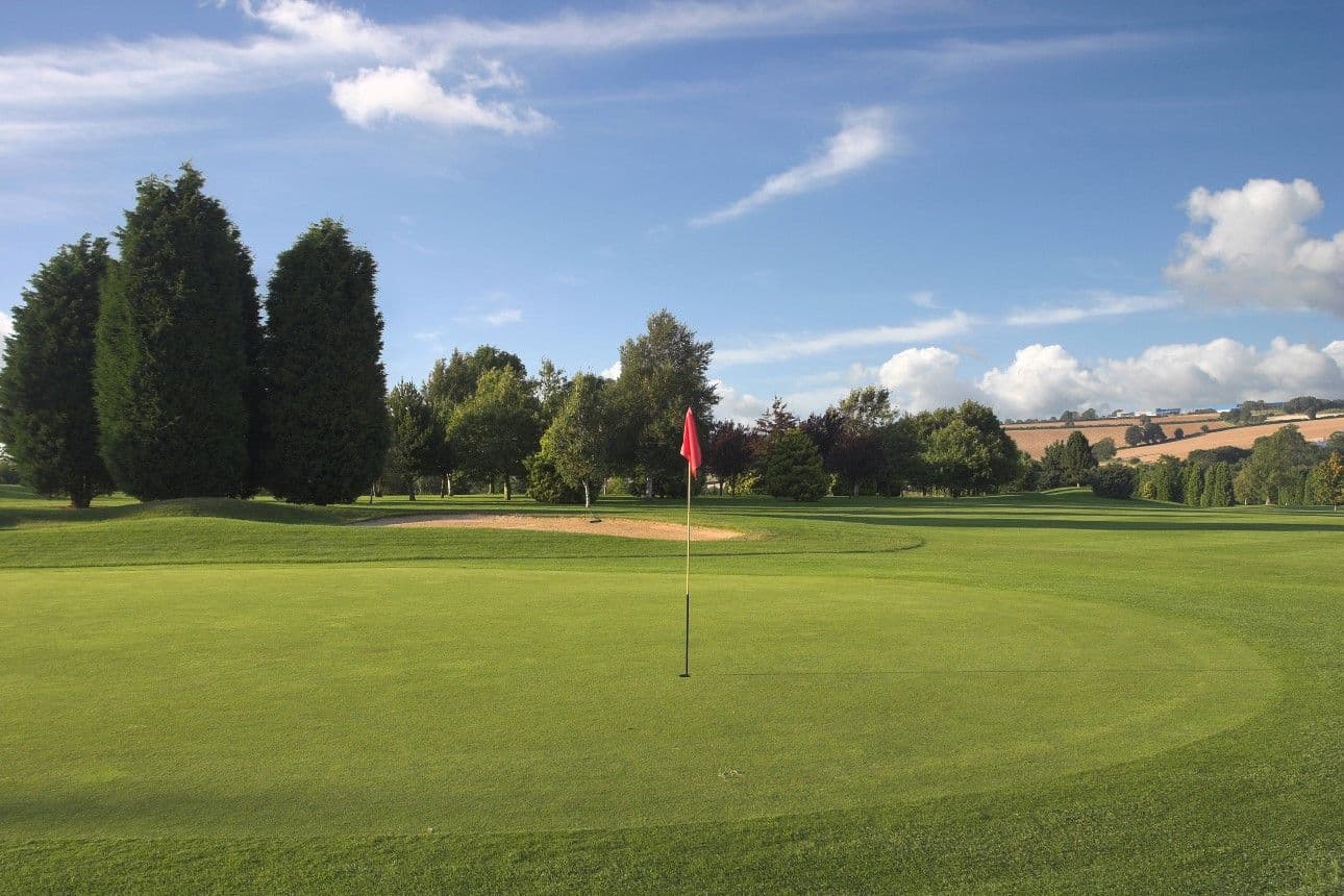 A smooth green with a red flagstick at Staverton Park Hotel & Golf Club