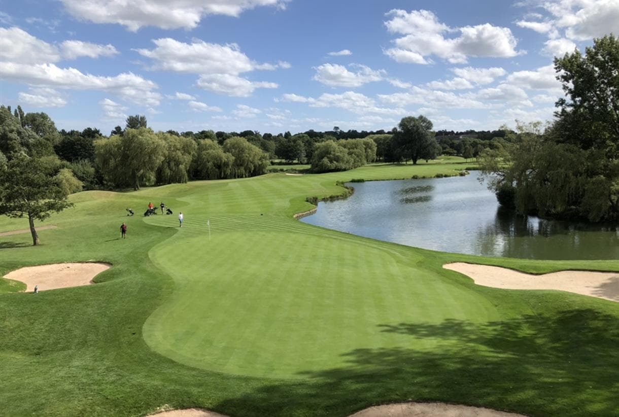 A well maintained fairway nestled with sand bunkers a water hazard